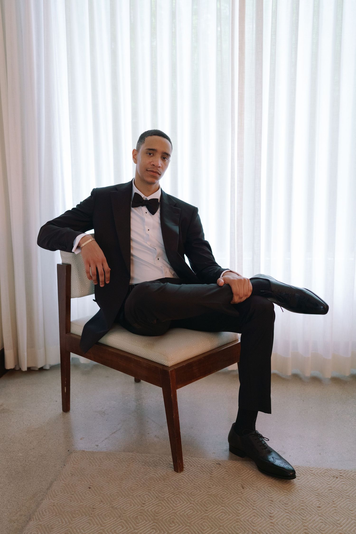 Formal portrait session showing relaxed poses on a wooden bench against white curtains.