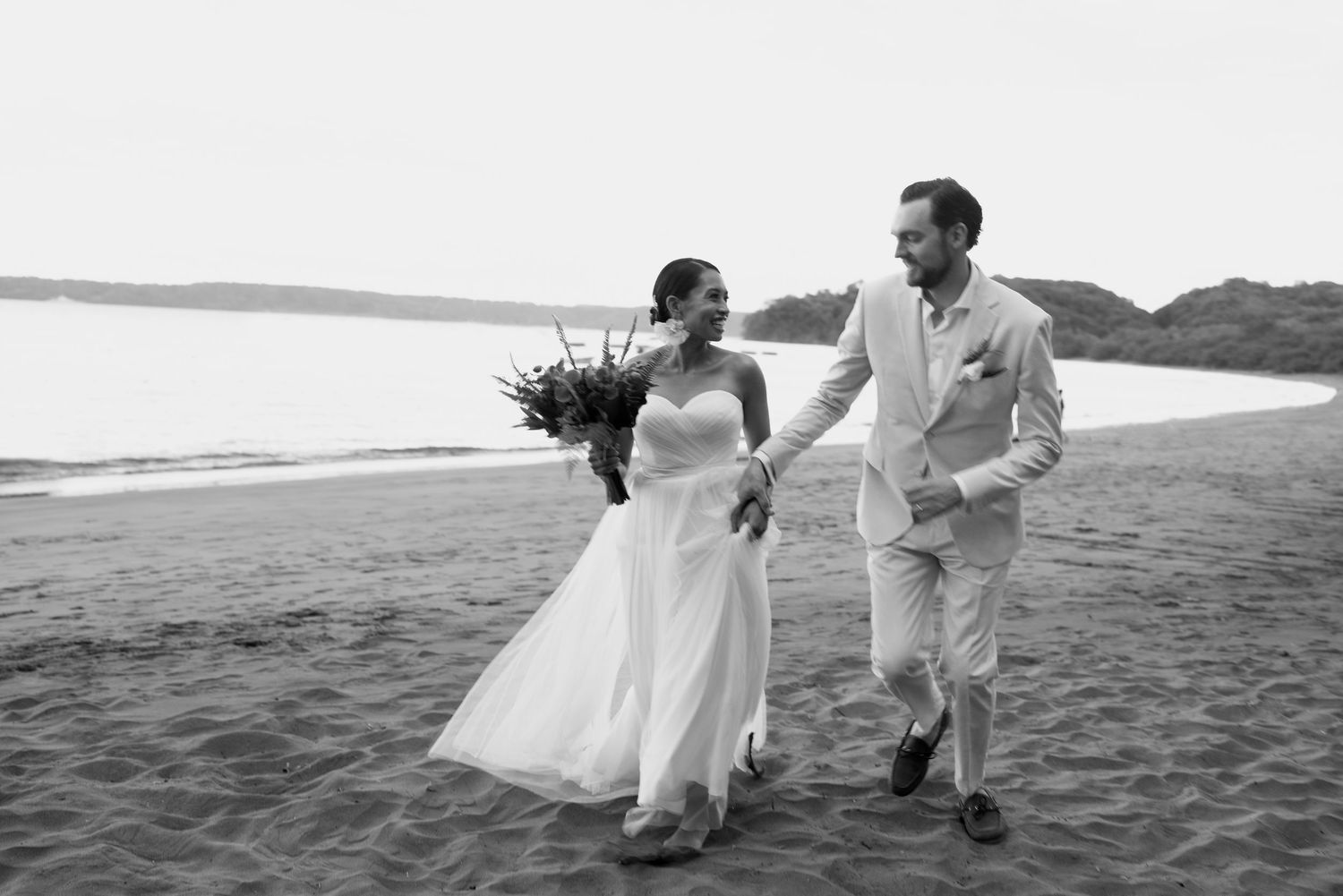 Dynamic wedding photos showing movement and joy on a sandy beach at sunset.