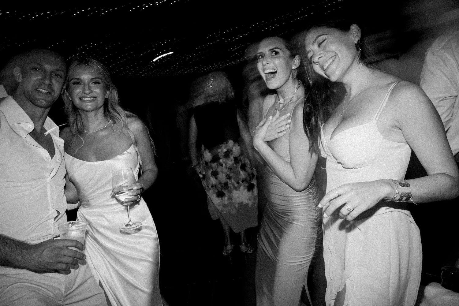 Guests dancing and celebrating at a lively wedding reception in black and white.
