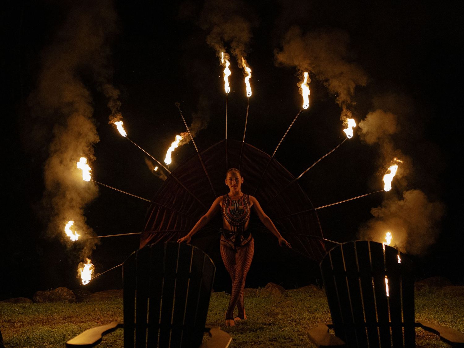 Fire dancers perform with flaming batons in a dramatic nighttime display at an outdoor event.