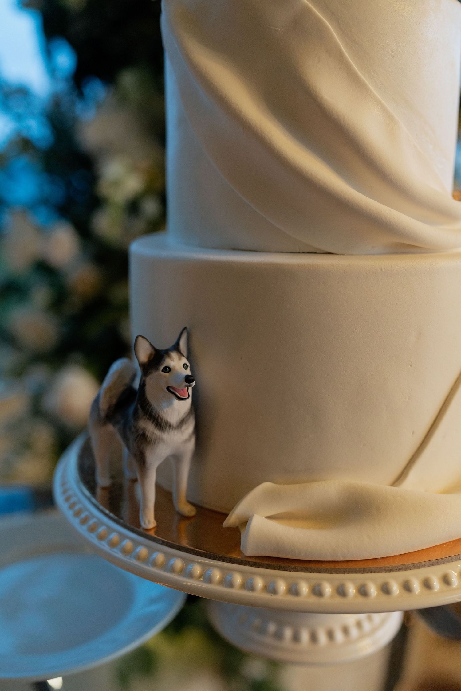 White wedding cake decorated with small husky dog figurines.