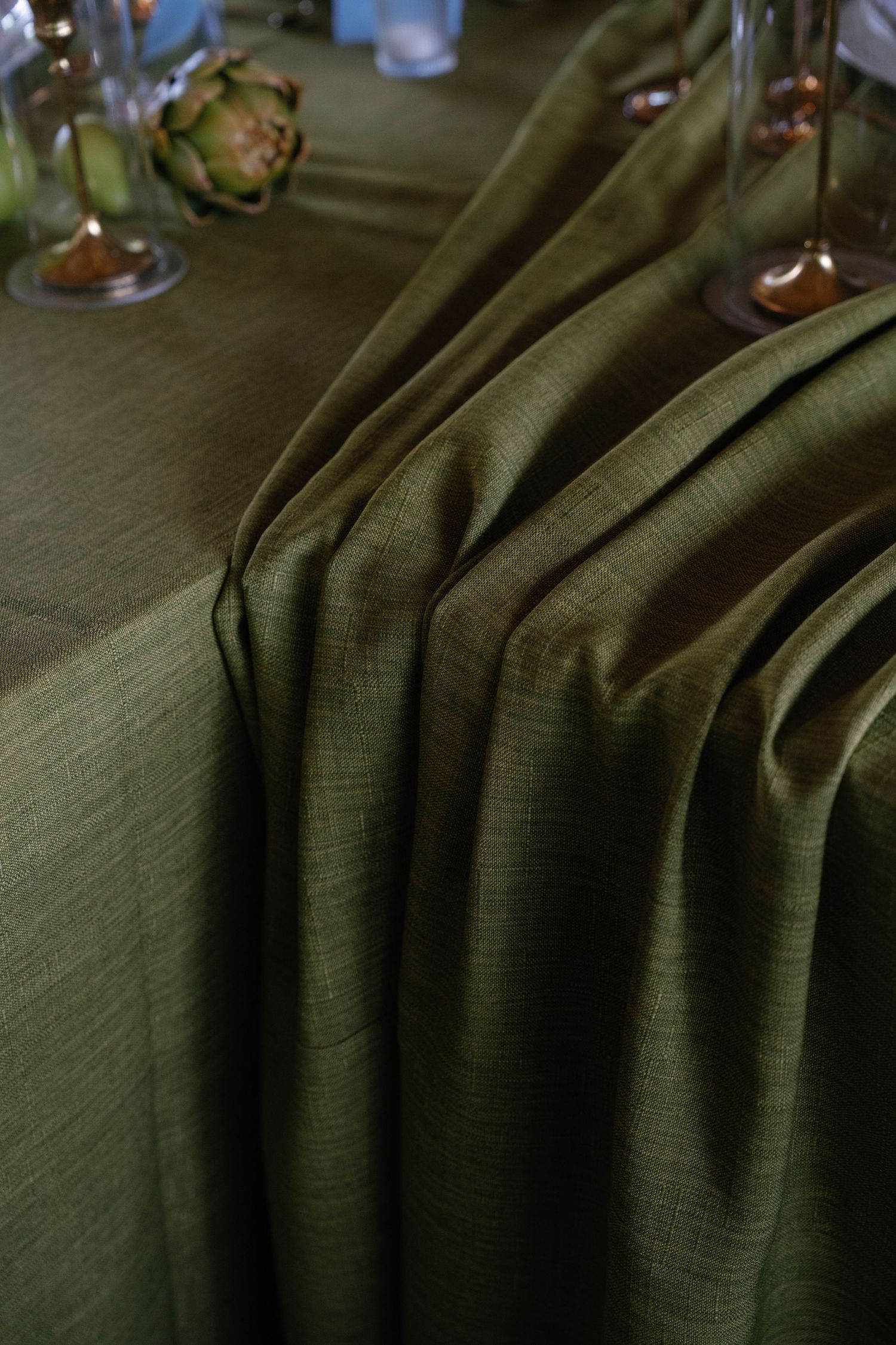 Close-up of draped olive green tablecloth fabric showing texture and folds.