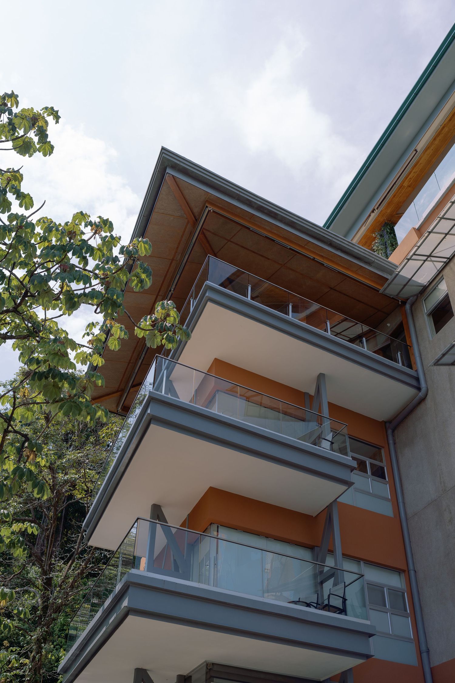 Modern apartment building exterior with glass balconies and wood accents.