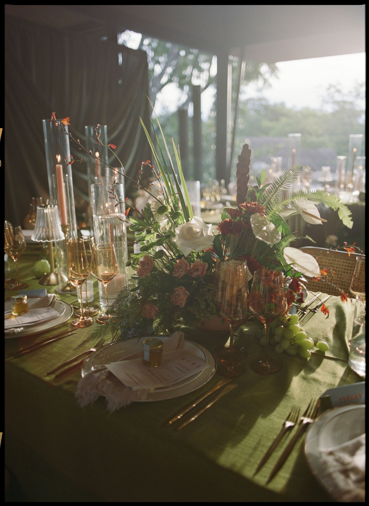 Elegant table setting with floral centerpieces and candlelight creating dramatic shadows.
