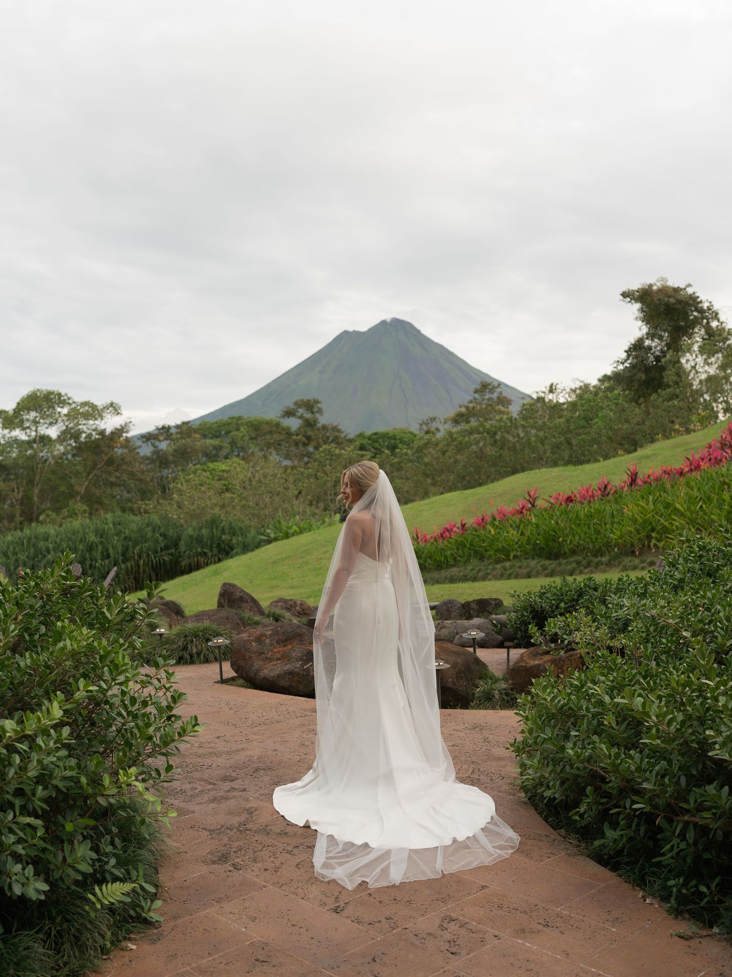 Scenic mountain landscape with a person in a wedding dress posing among greenery.