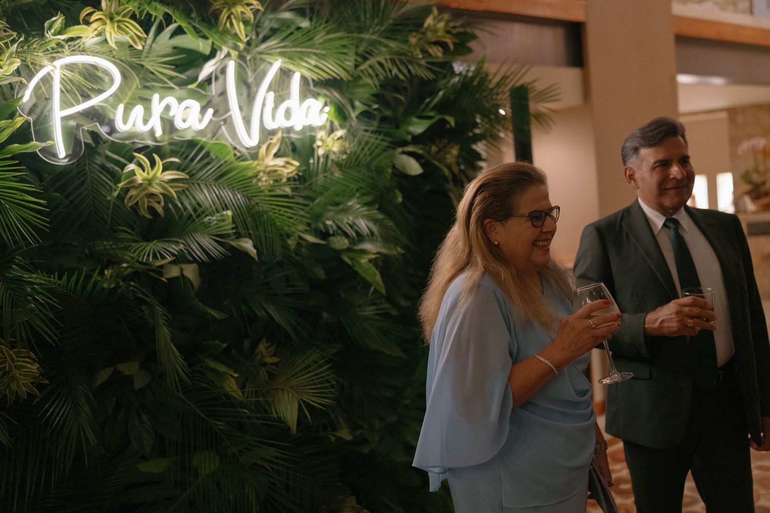 Tropical wedding venue decorated with plants and a neon 'Pura Vida' sign.