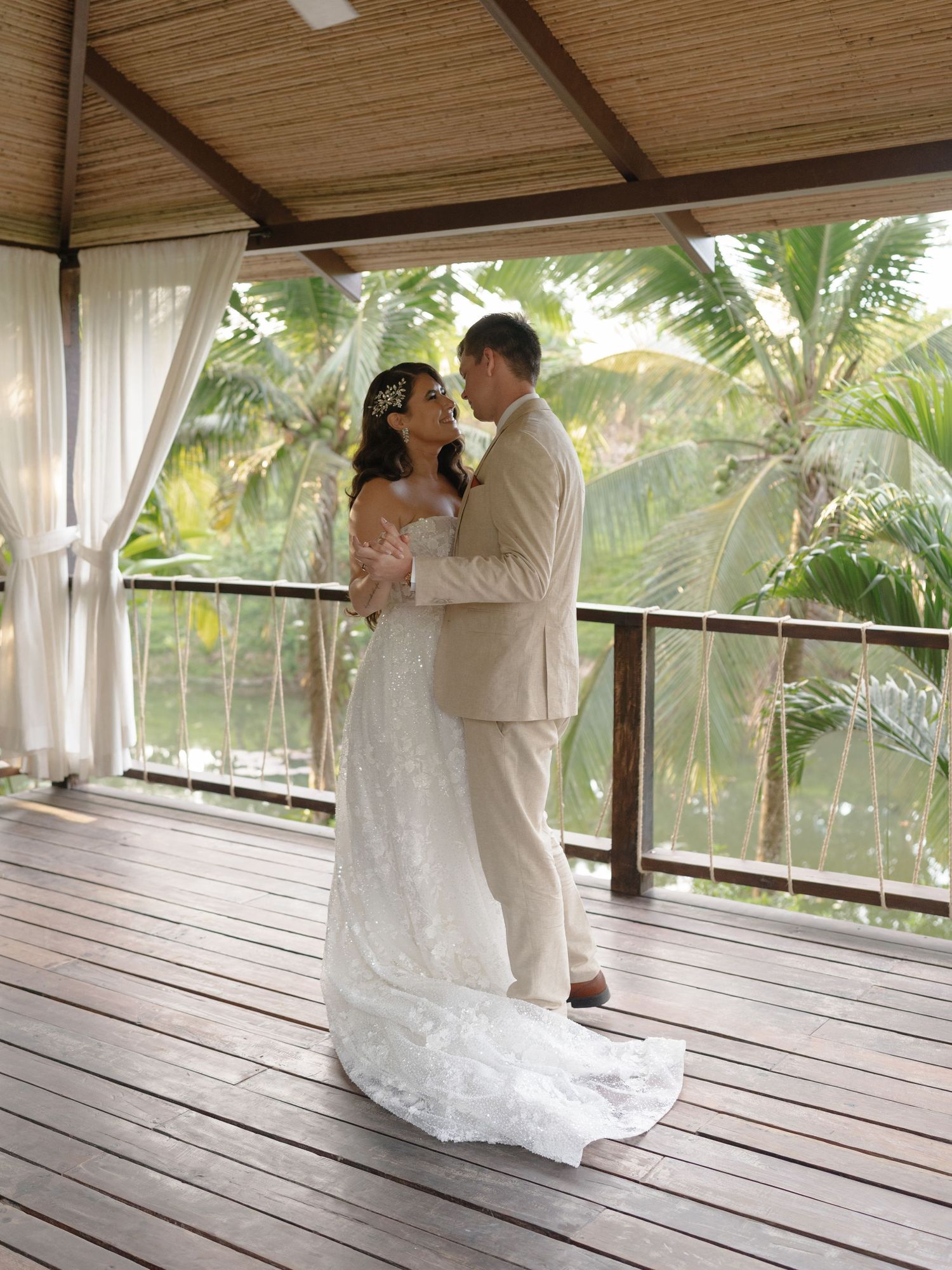 Wedding couple dancing on a covered wooden deck with tropical foliage in the background.