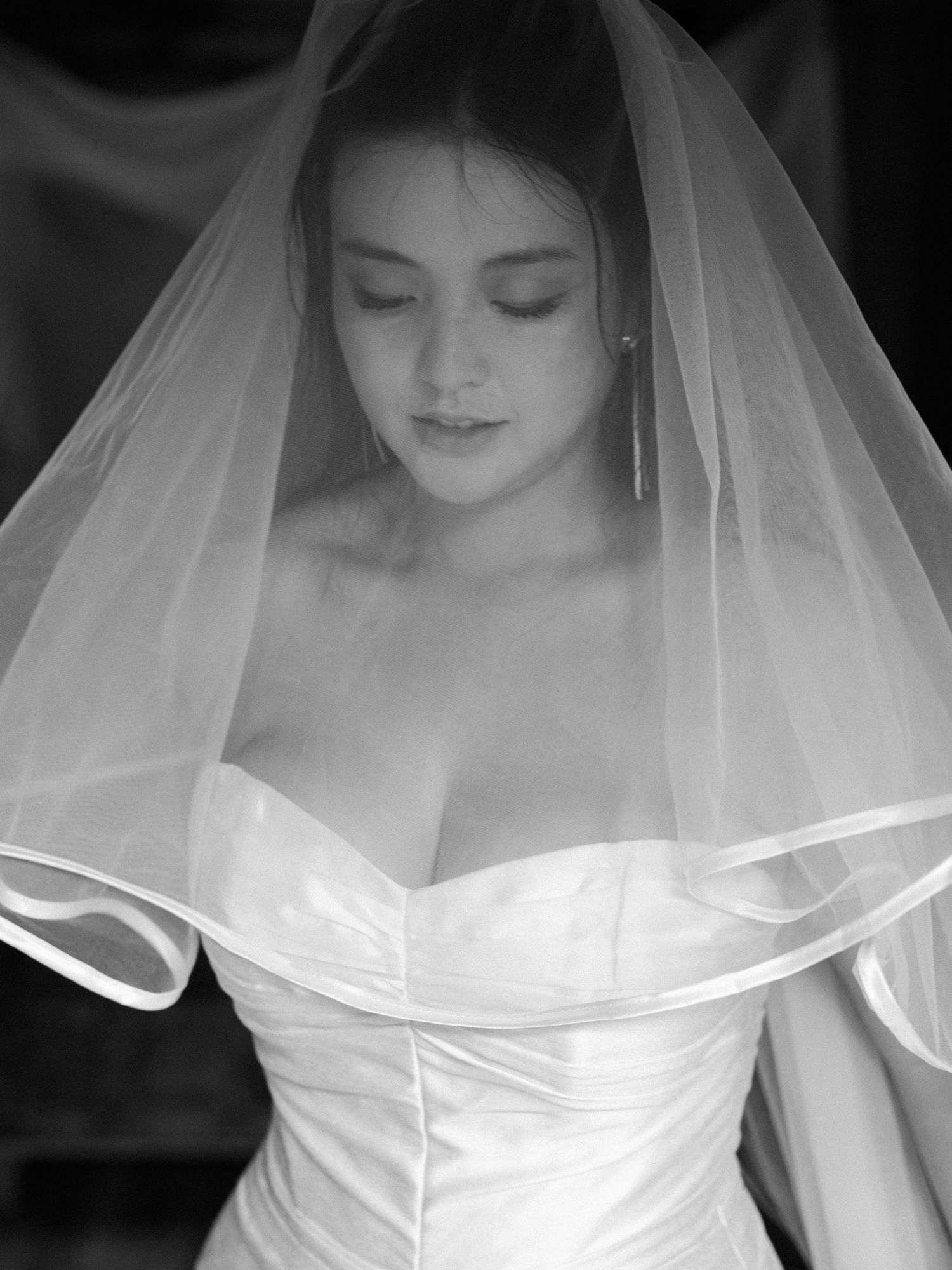 Close-up black and white portrait shots showing details of a wedding veil and dress.