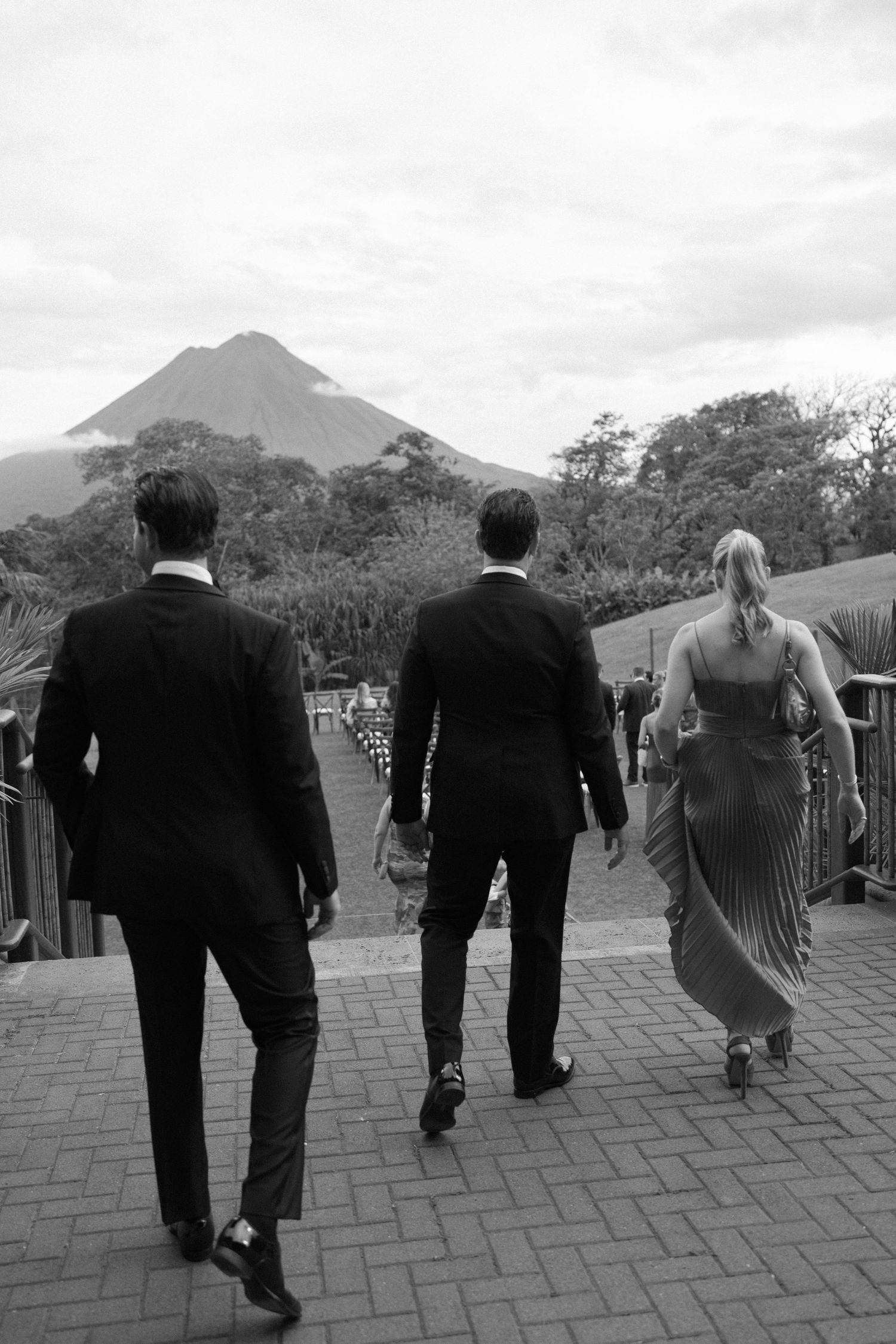 Wedding party walking along a stone path with mountain views in the background.