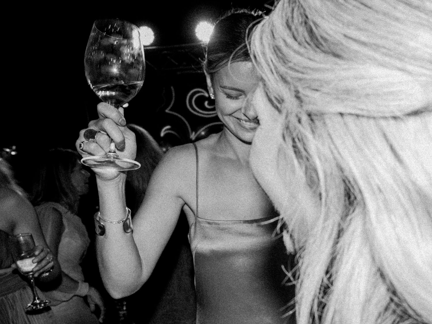 Black and white party scene with celebratory wine glasses raised.