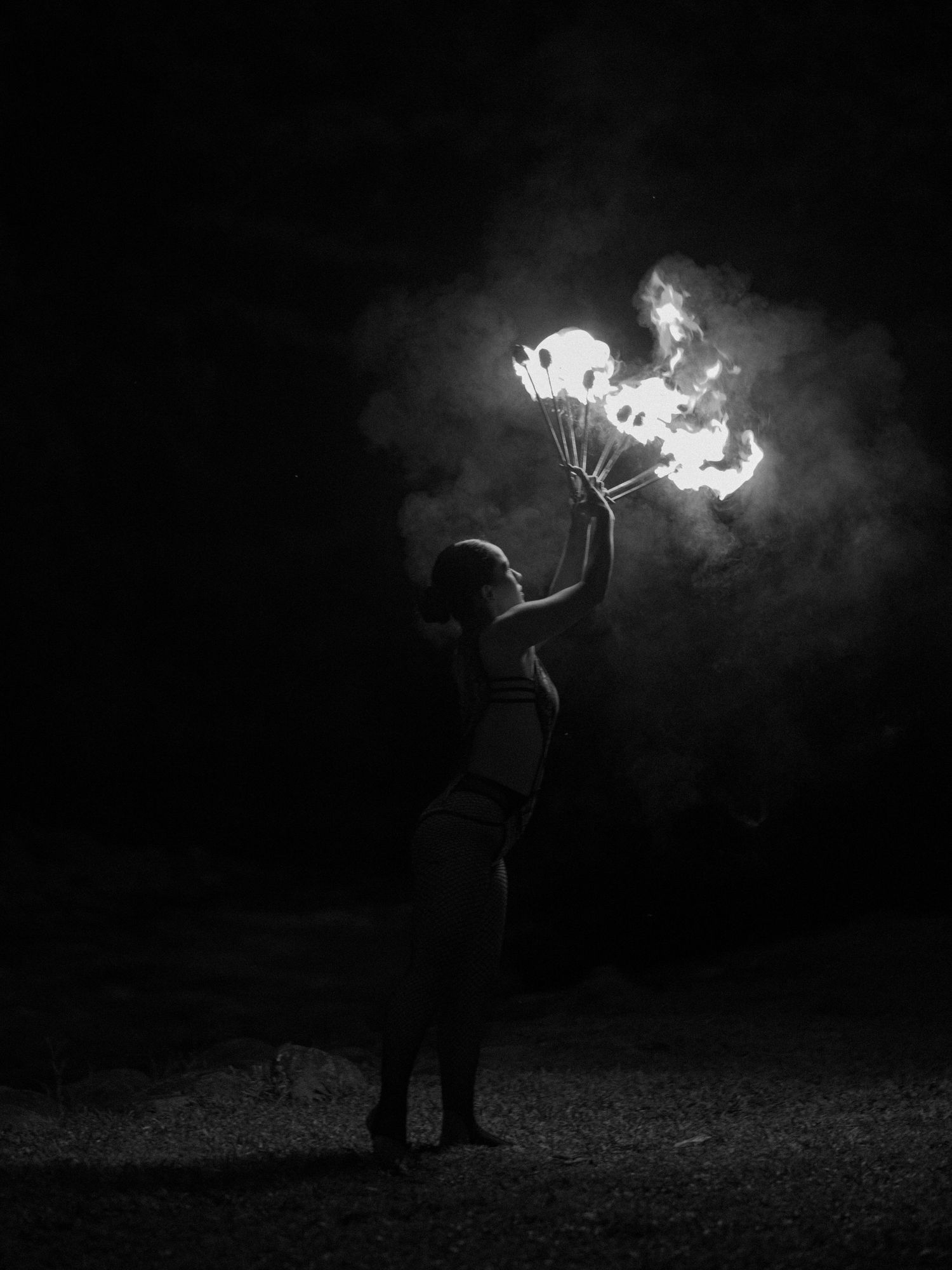 Dramatic black and white photo of a fire performer creating swirling patterns in the darkness.