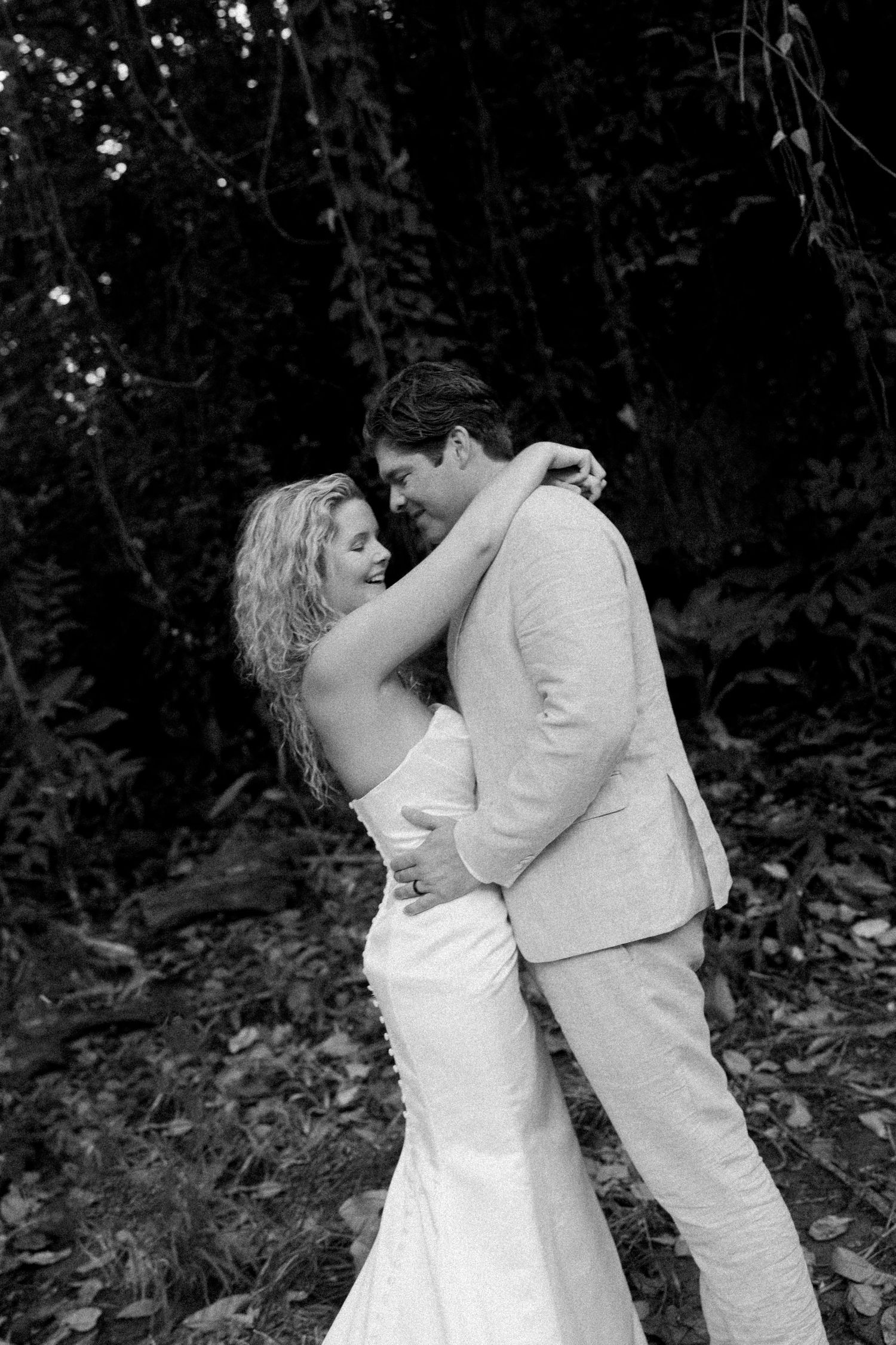 A tender dance moment captured in black and white against a forest backdrop.