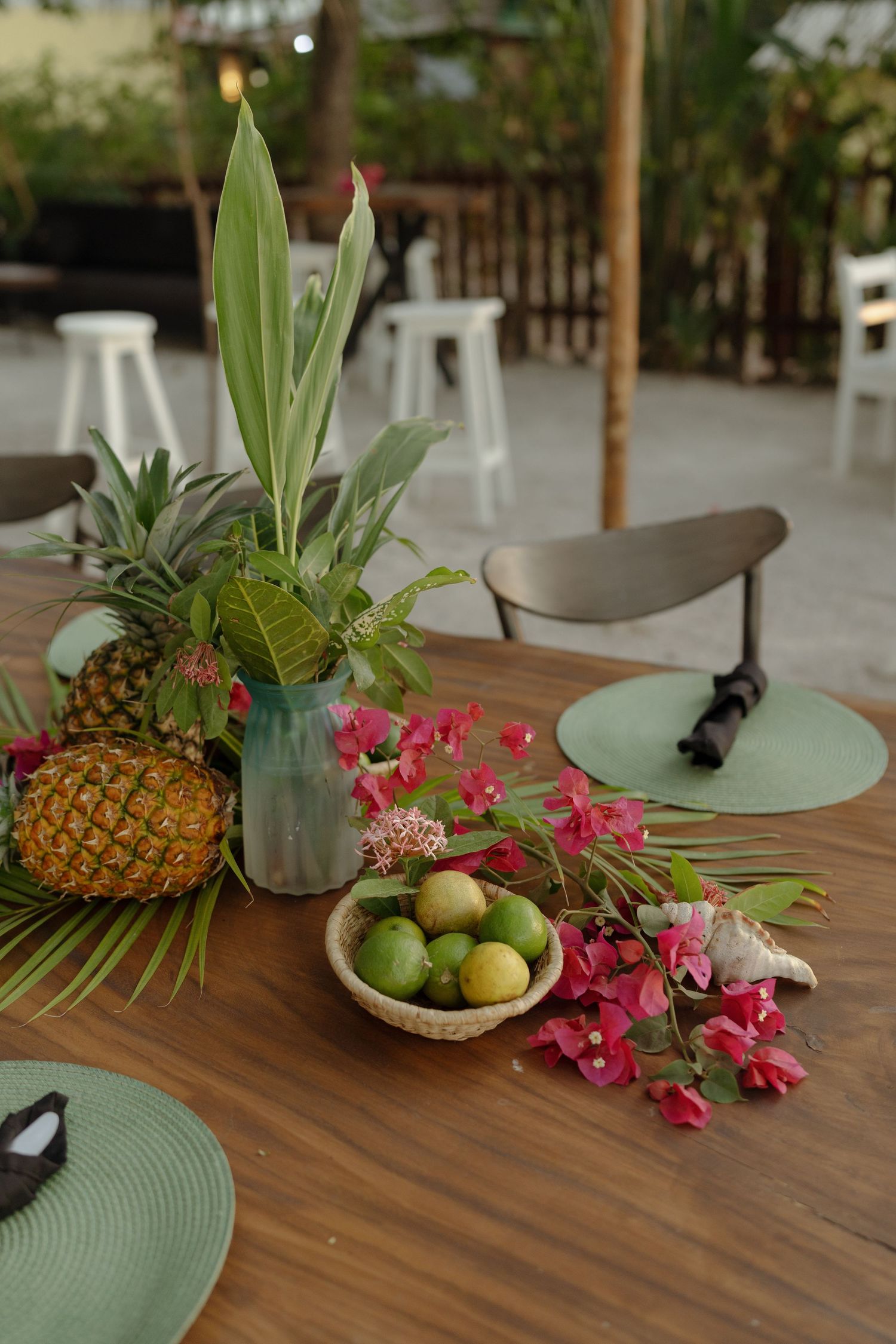 Tropical table decor featuring pineapples, orchids, and green placemats on wooden surfaces.