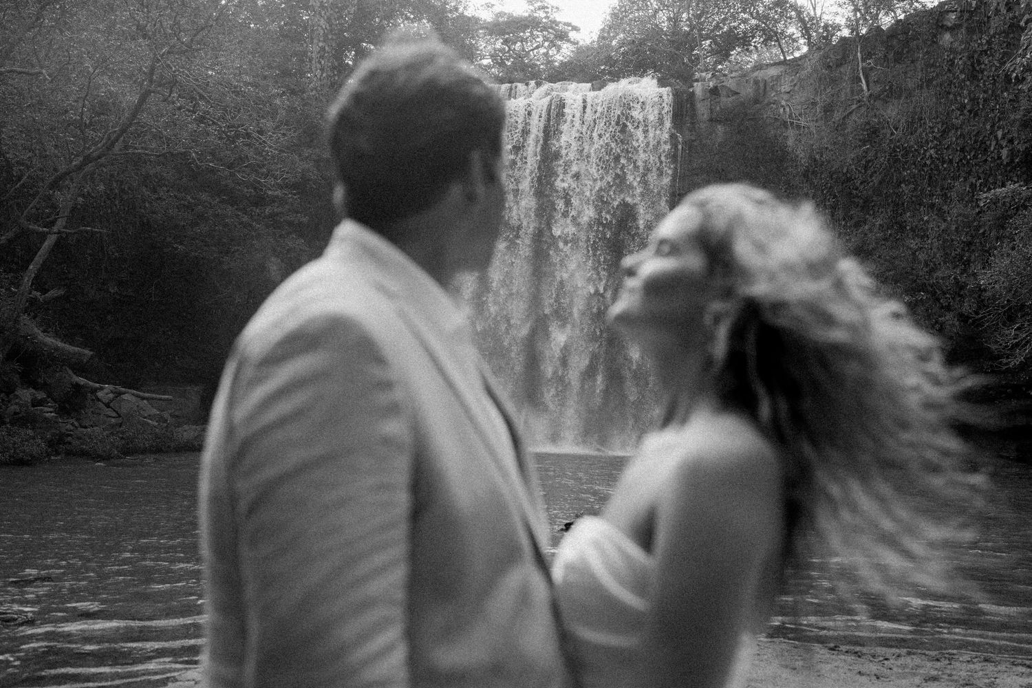 Artistic black and white sequence of a couple's romantic moments near a waterfall.