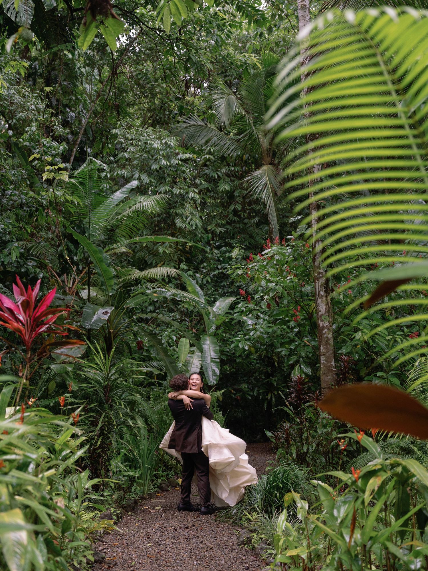 A wedding photography session in a tropical garden surrounded by palm fronds and exotic plants.