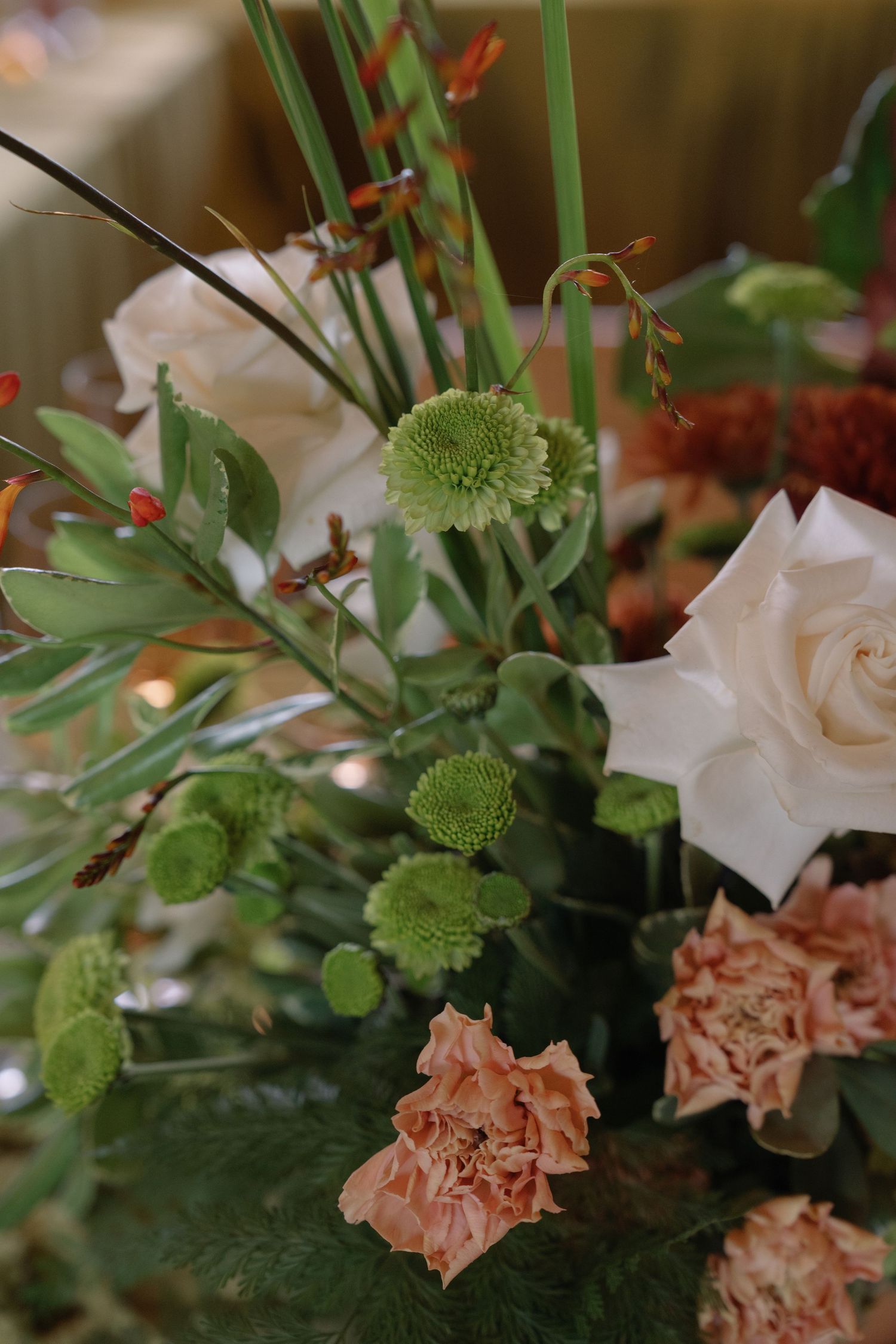 Elegant floral centerpiece with white roses, green chrysanthemums and delicate foliage.