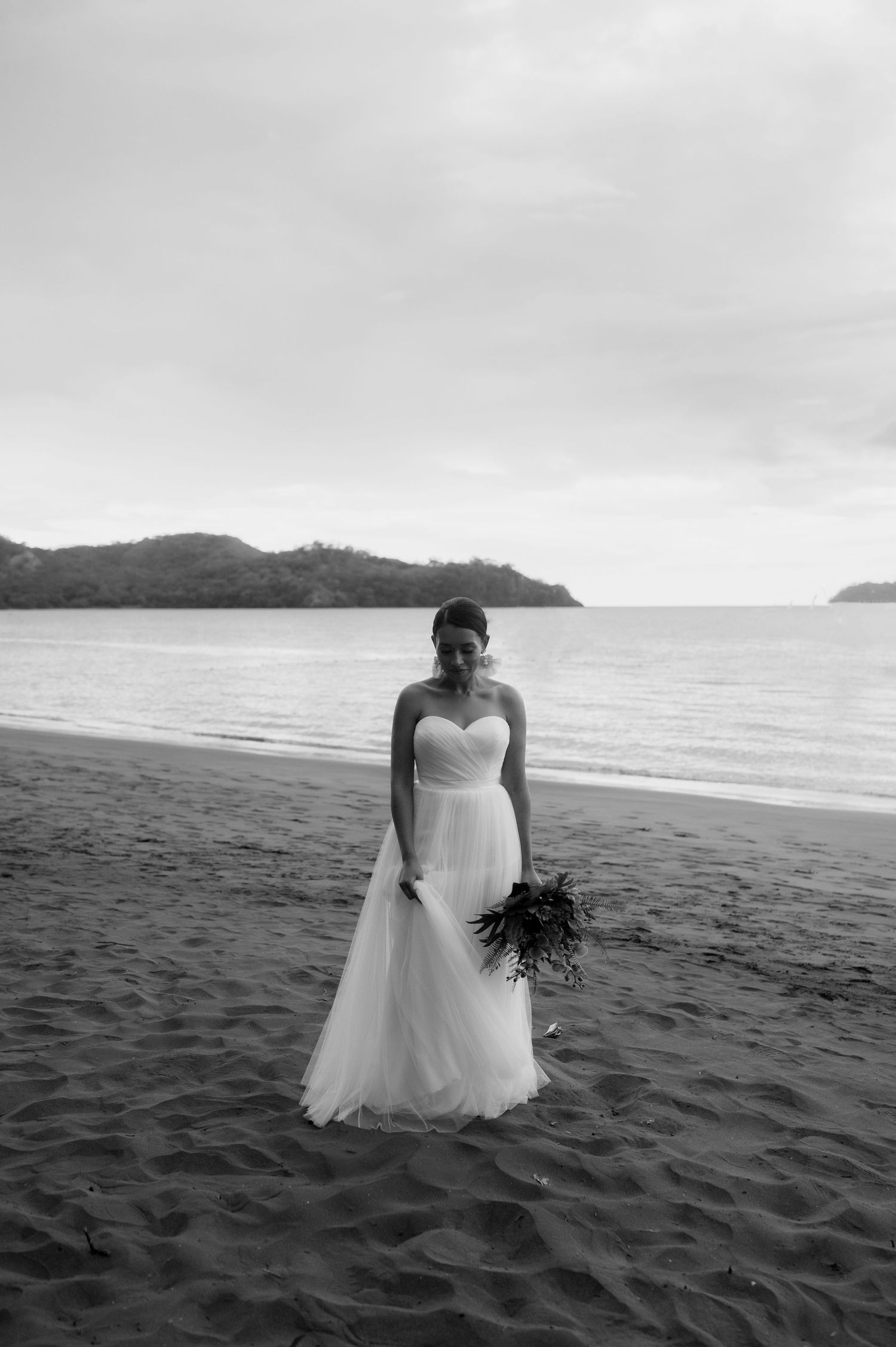 A series of black and white photos showing a bride in a flowing dress on a sandy beach.