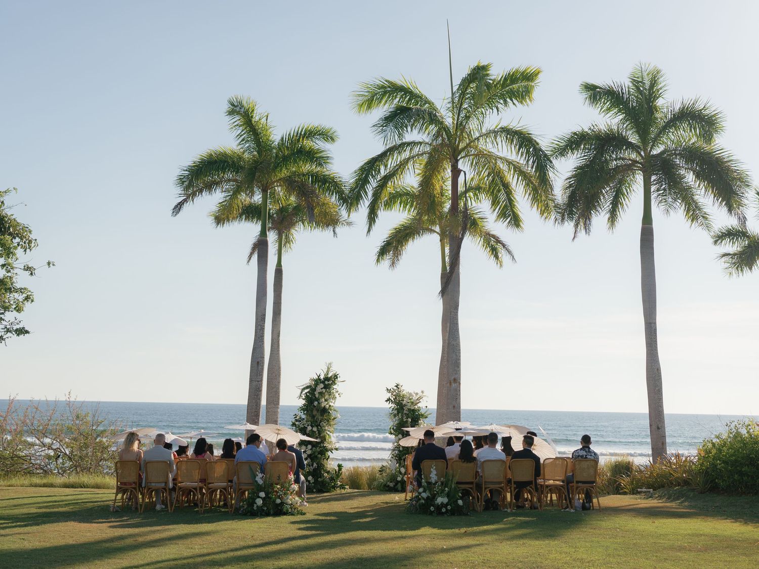 Palm trees line a beachfront wedding ceremony location at sunset.