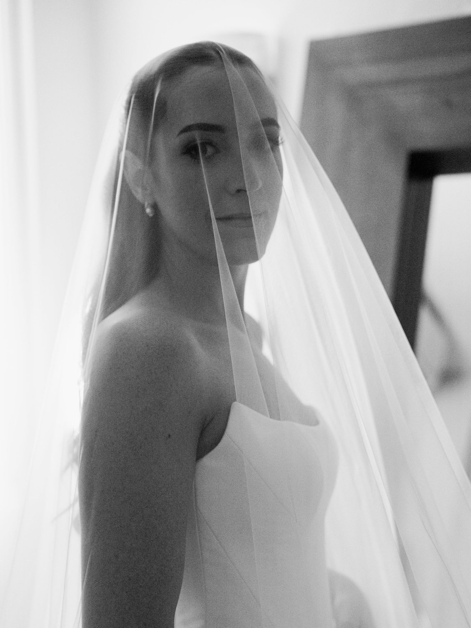 A black and white portrait series showing a figure behind sheer white fabric creating an ethereal veiled effect.