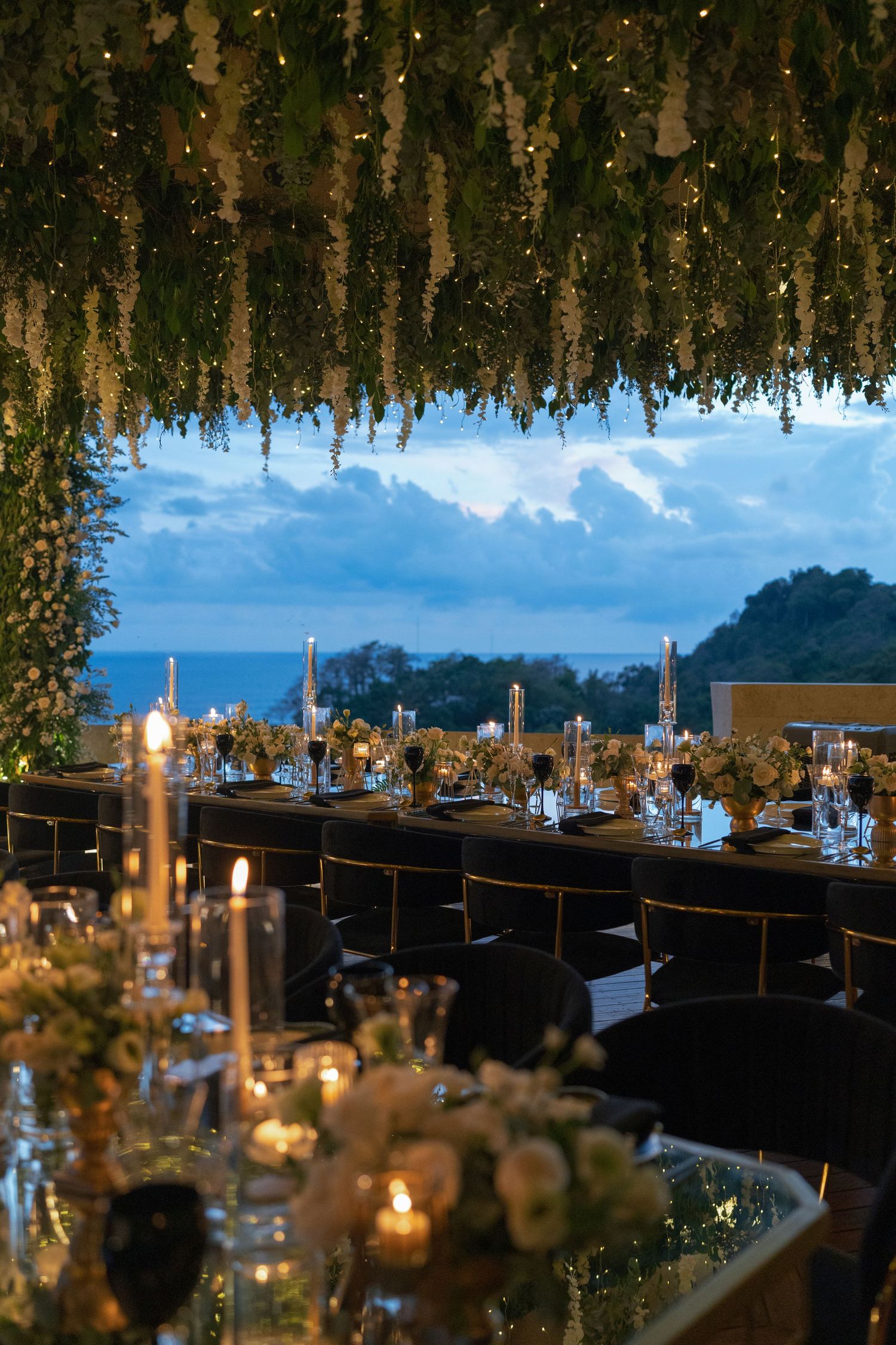 Romantic reception setup with hanging greenery and twinkling lights creating a magical evening ambiance.