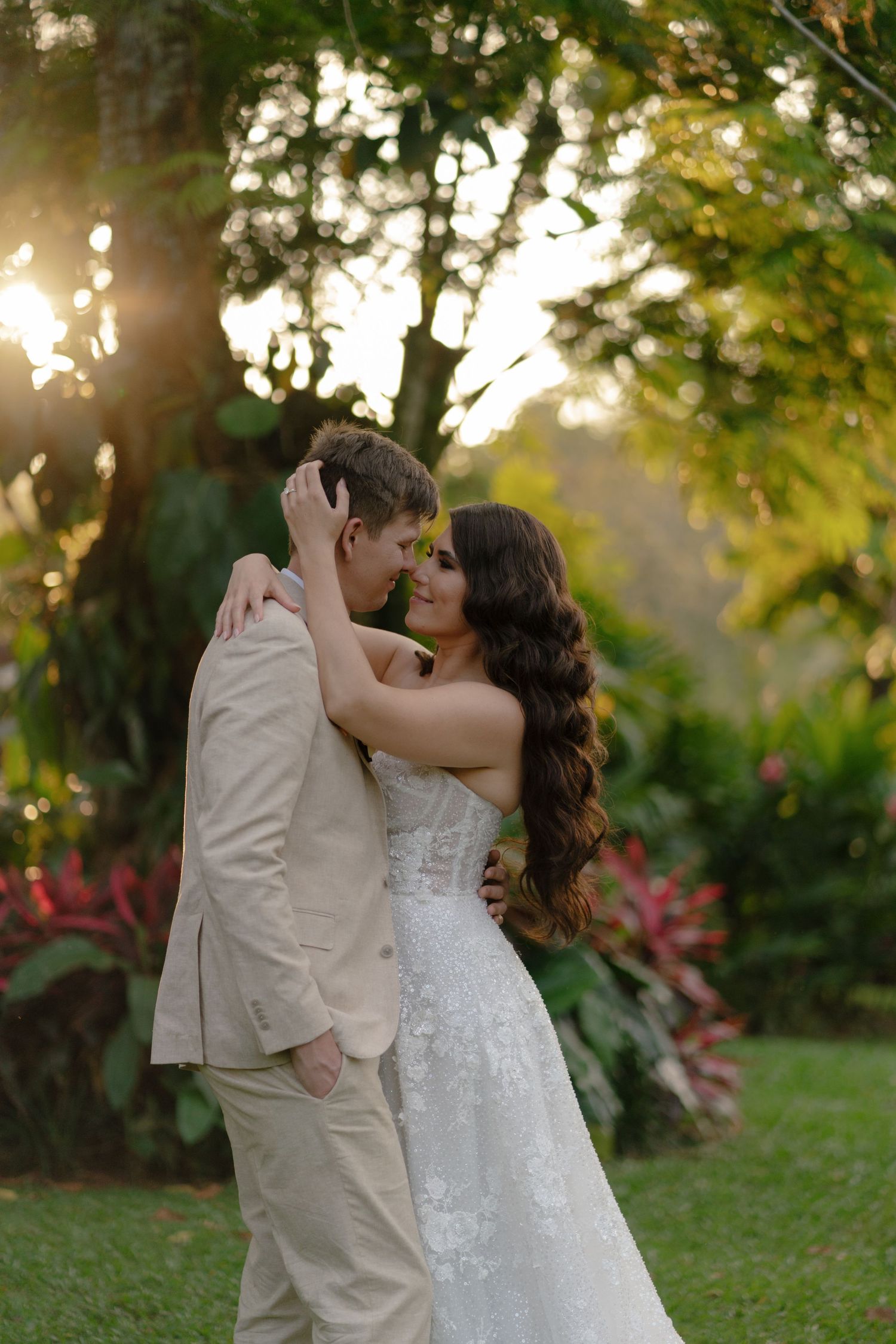 Romantic wedding couple shares intimate moments in a garden at sunset.