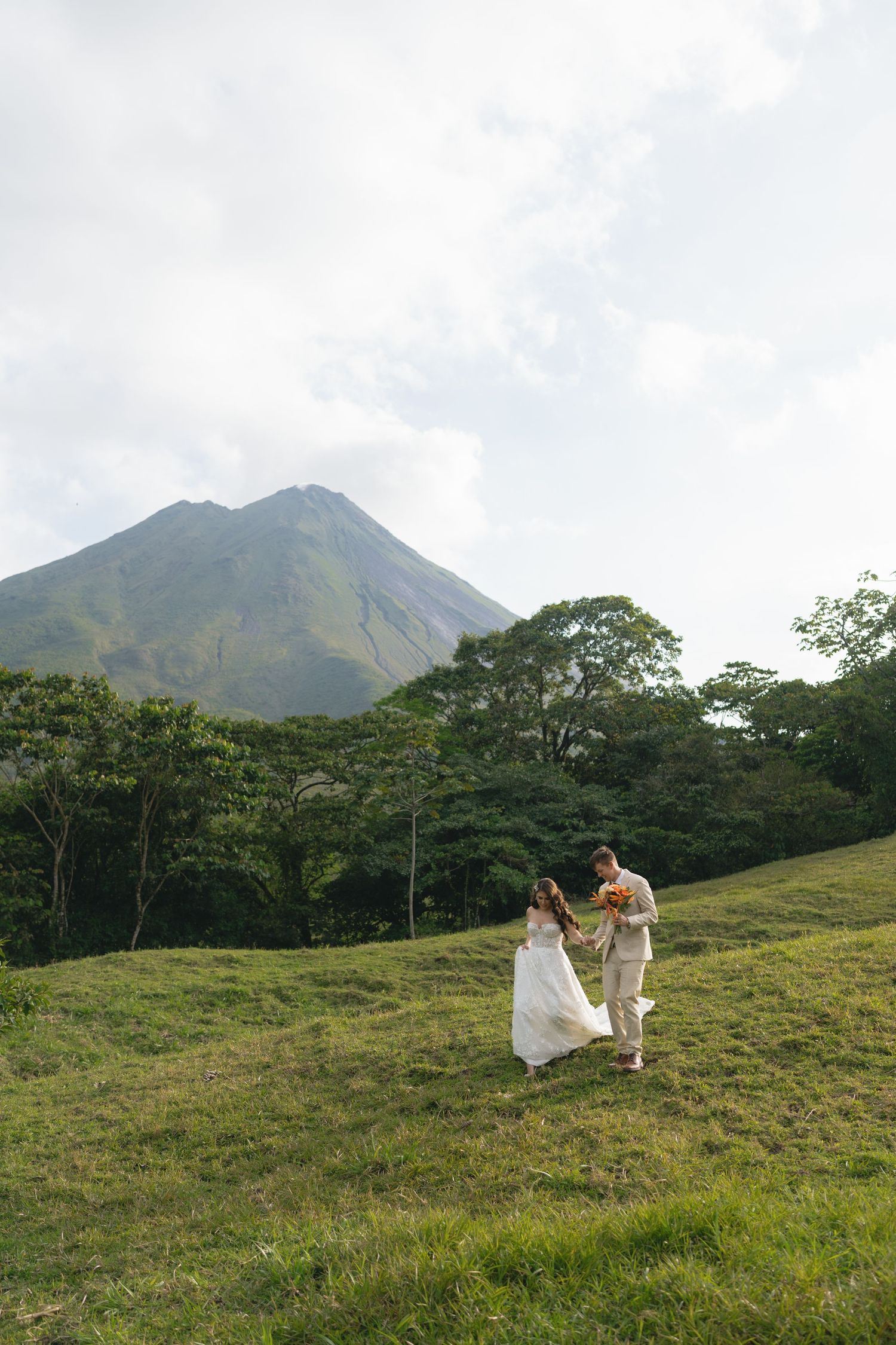 Wedding photography session on rolling green hills with volcanic mountains in distance.