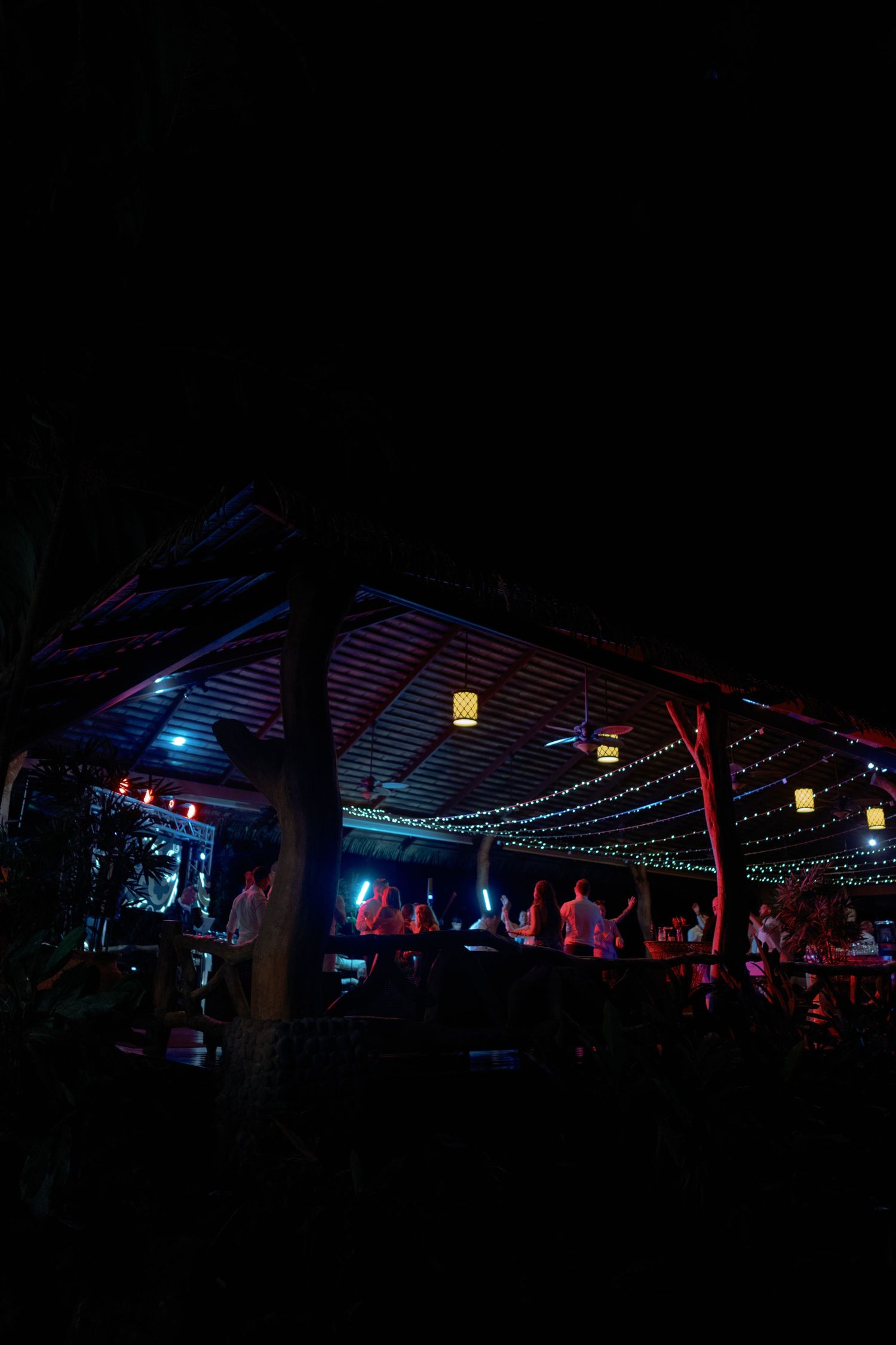 Nighttime outdoor venue illuminated with colorful lights and string lighting.