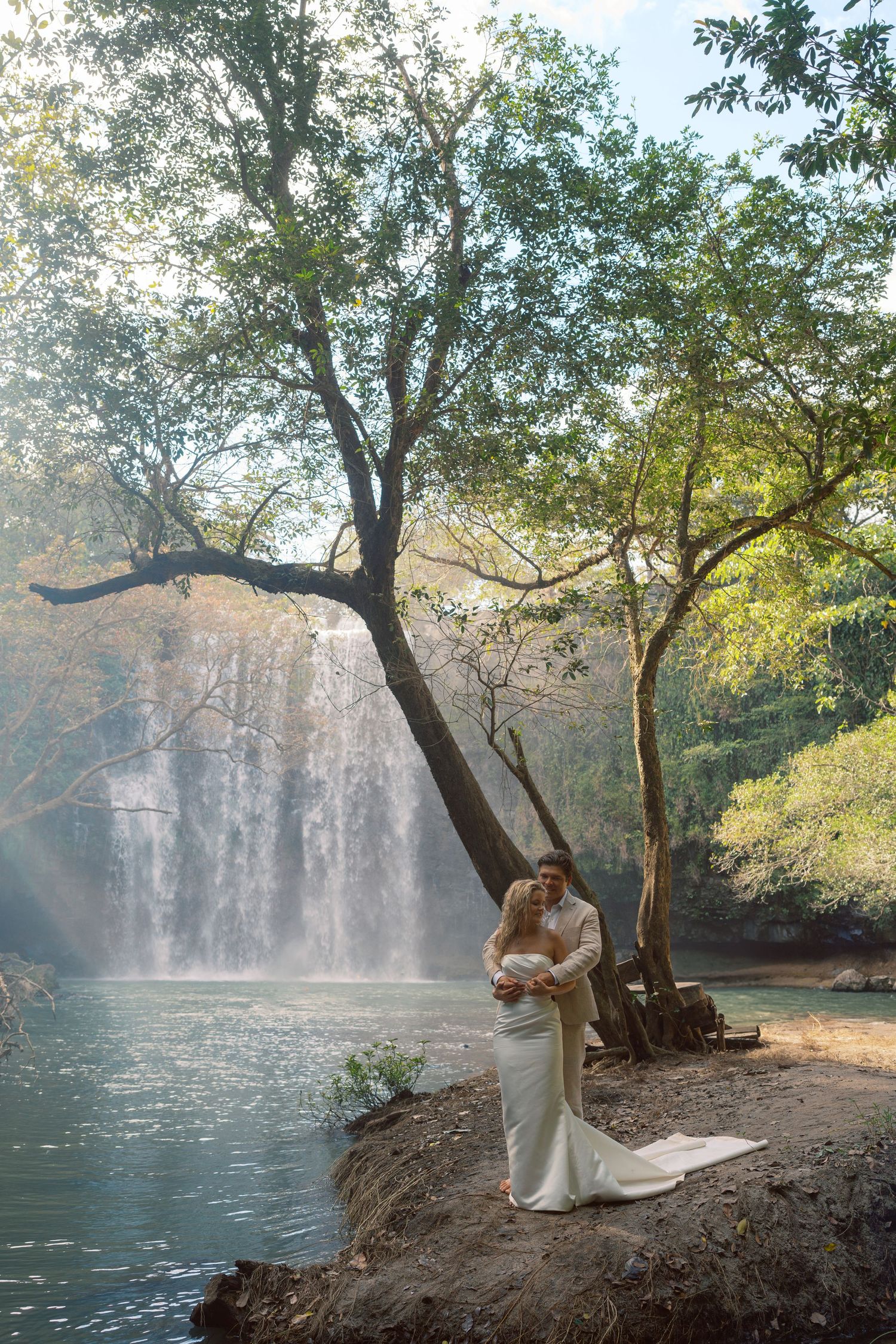 Wedding photography session at a scenic waterfall location with natural lighting.