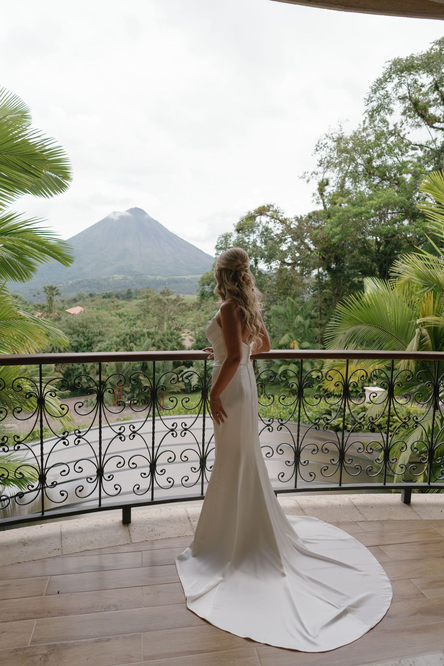 Bride twirling in white dress on balcony with mountain view backdrop.