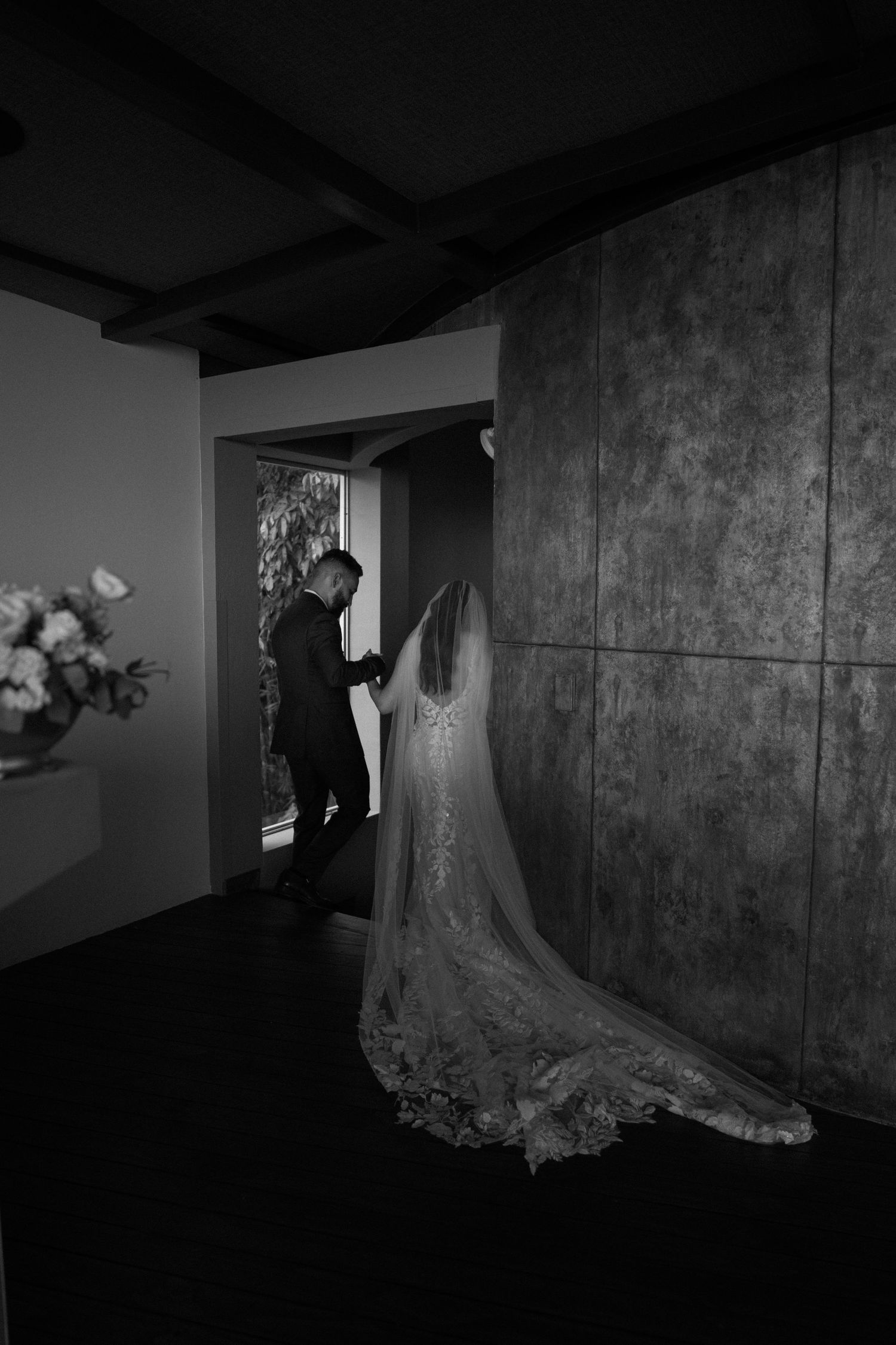 Black and white photos showing an elegant wedding dress displayed in a dimly lit hallway.