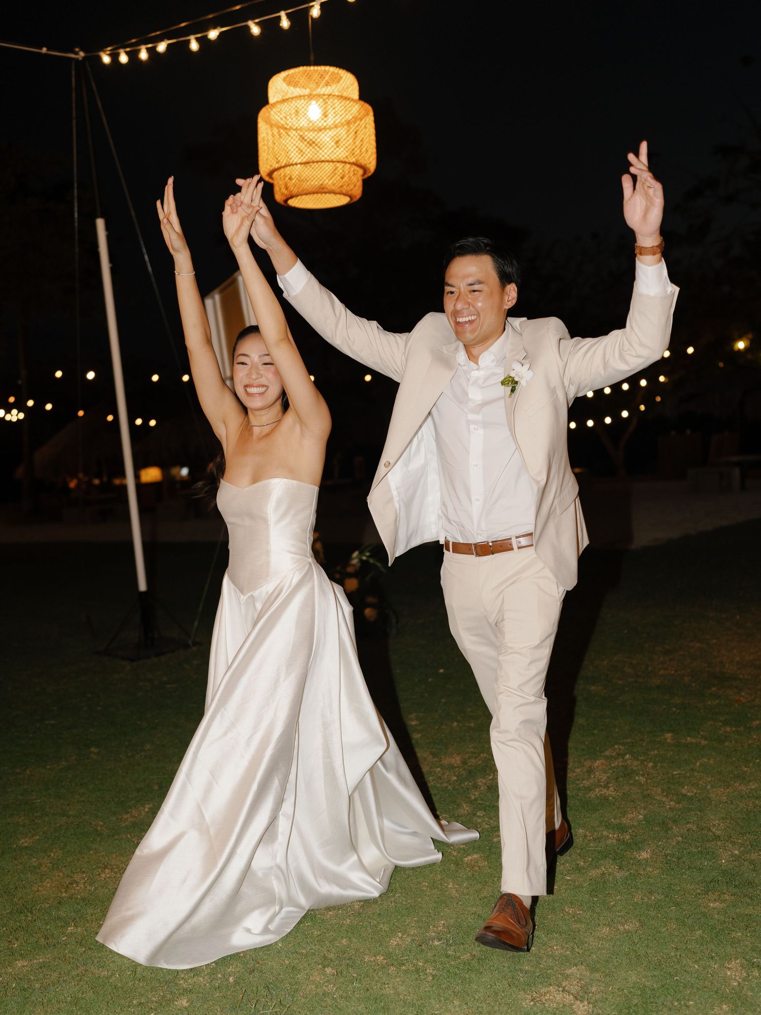 A joyful wedding couple dancing and celebrating at their outdoor reception.