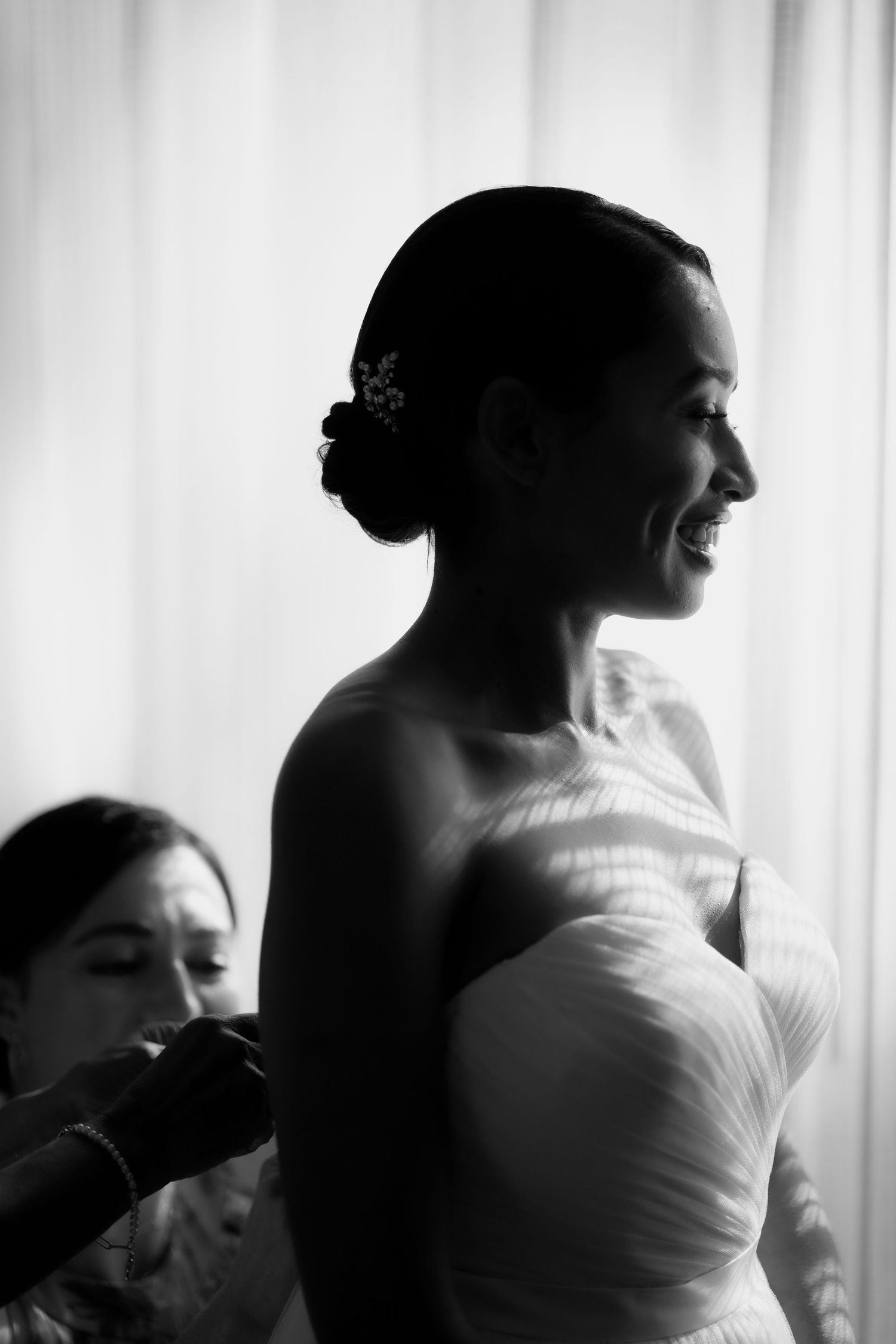 Artistic black and white silhouettes of a bride in dramatic lighting against white curtains.