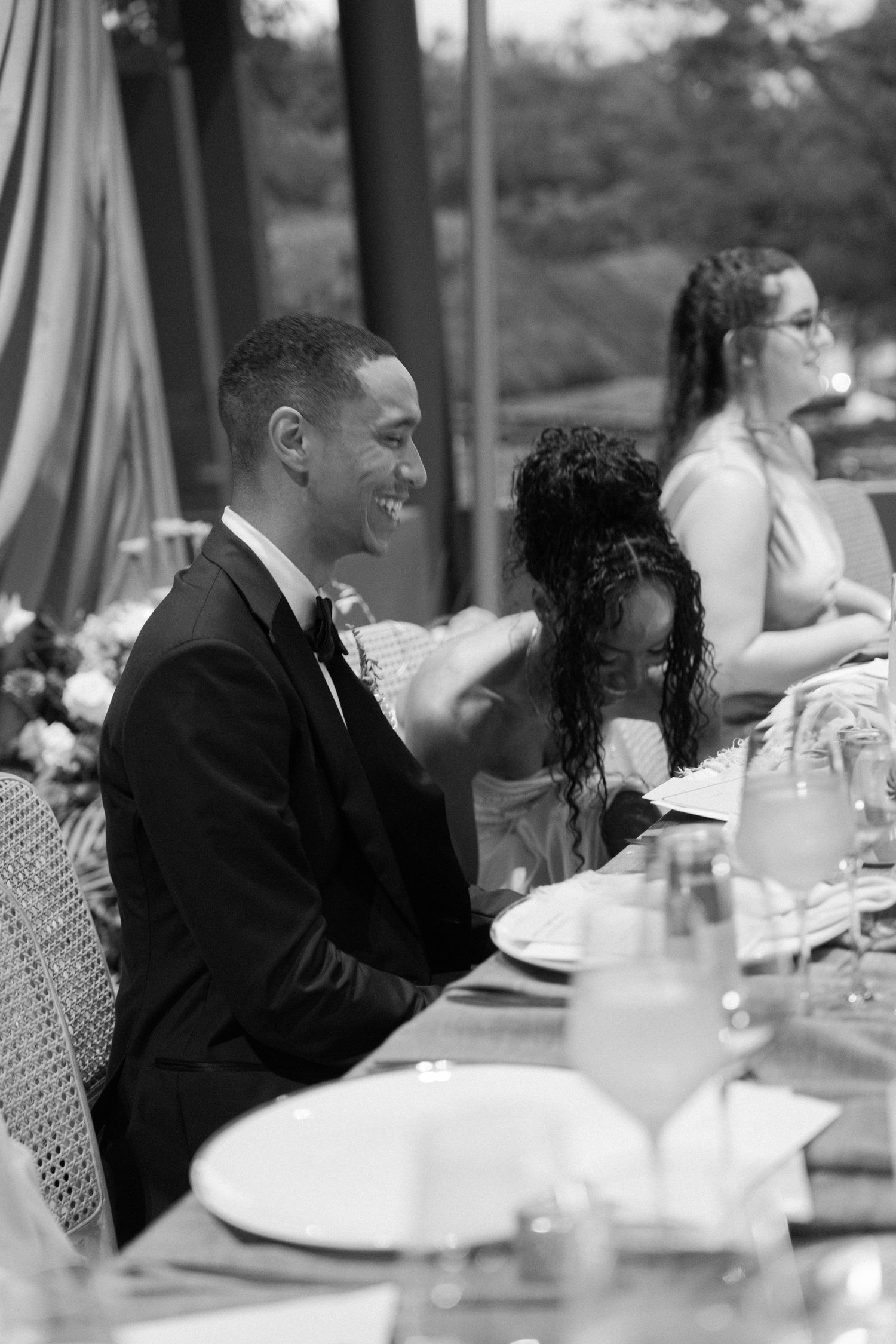 Wedding reception dinner scene with guests seated at elegantly decorated tables outdoors.