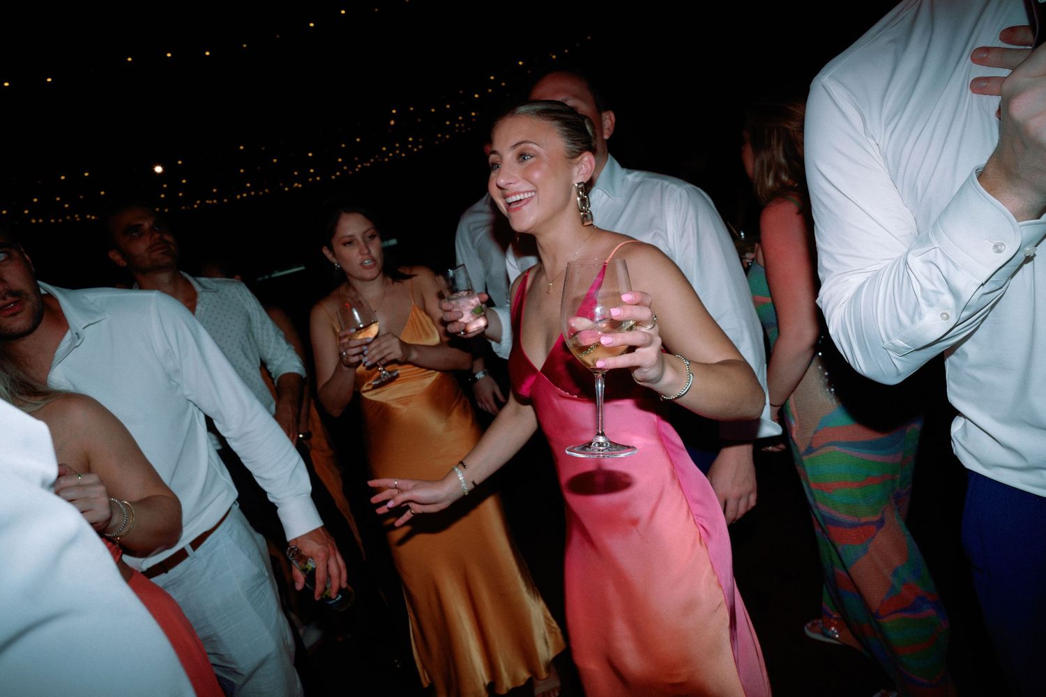 Wedding reception party guests dancing in dim lighting.