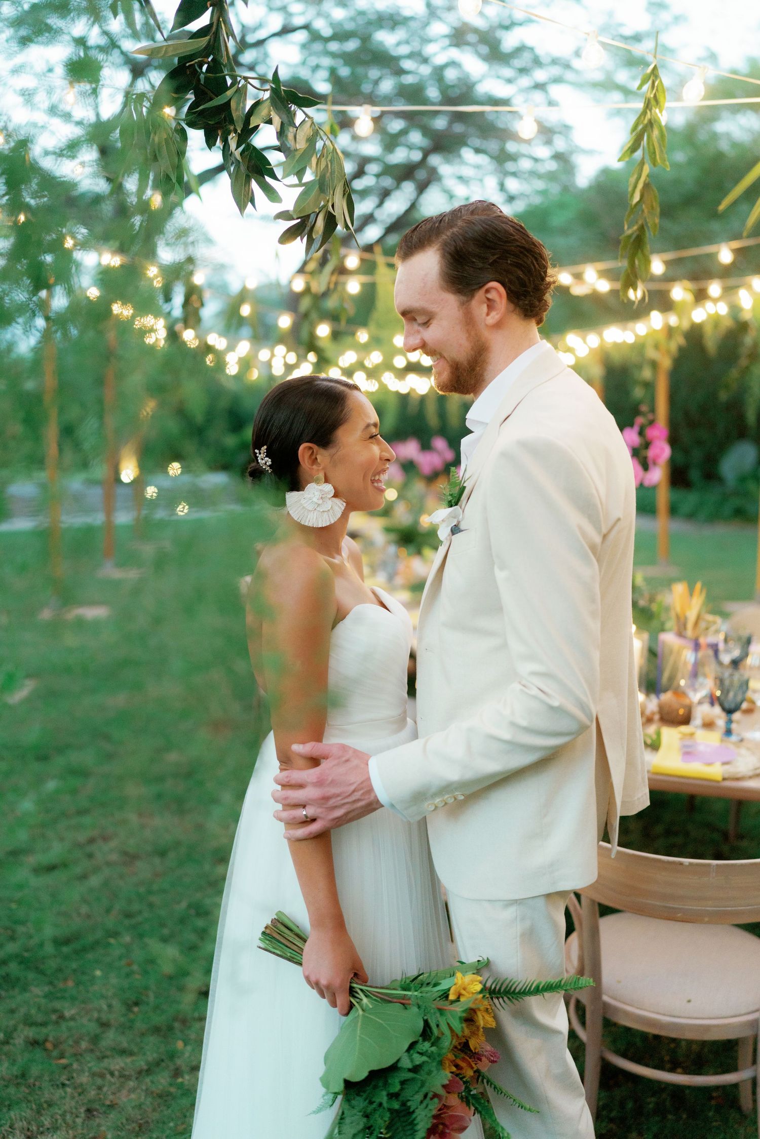Newlyweds sharing intimate moments under string lights at outdoor garden reception.