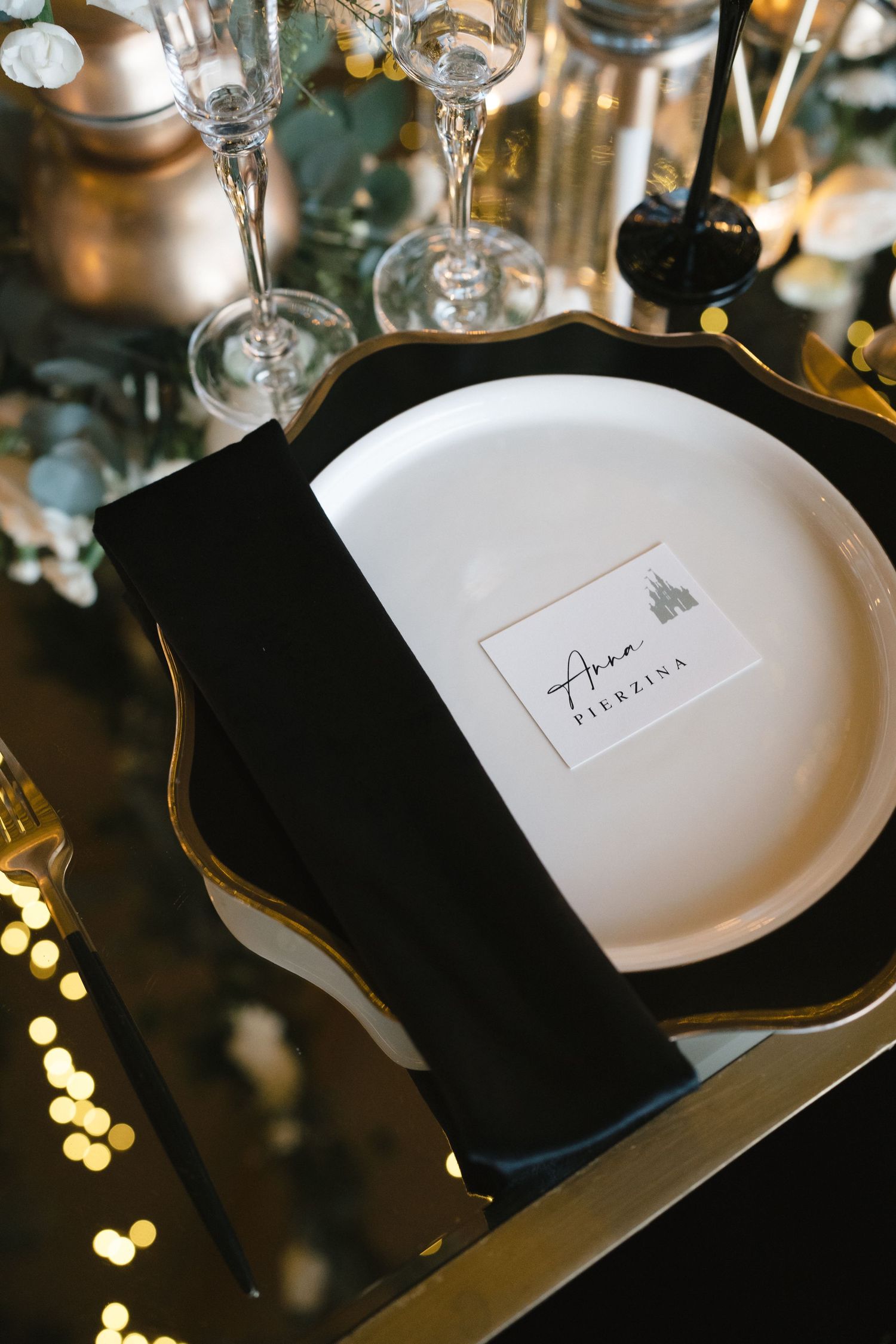 Elegant place settings with black napkins and white plates at a formal dinner reception.