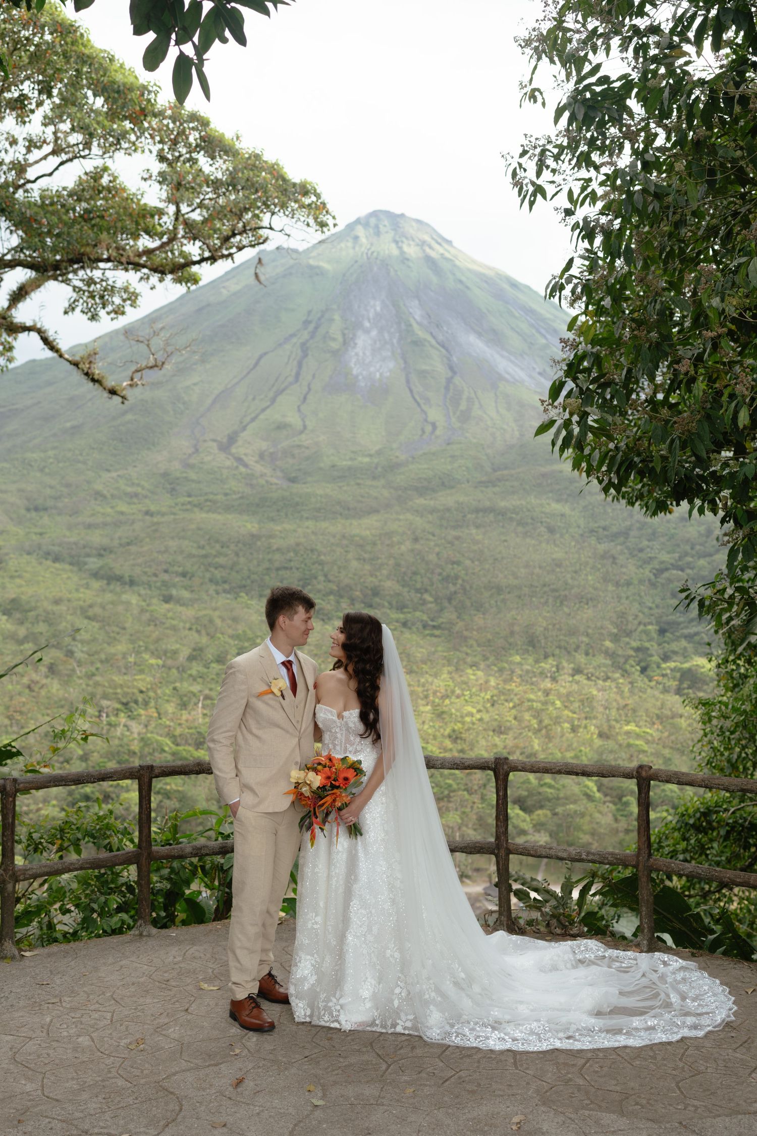 Romantic wedding portraits on scenic overlook with Arenal Volcano in background.