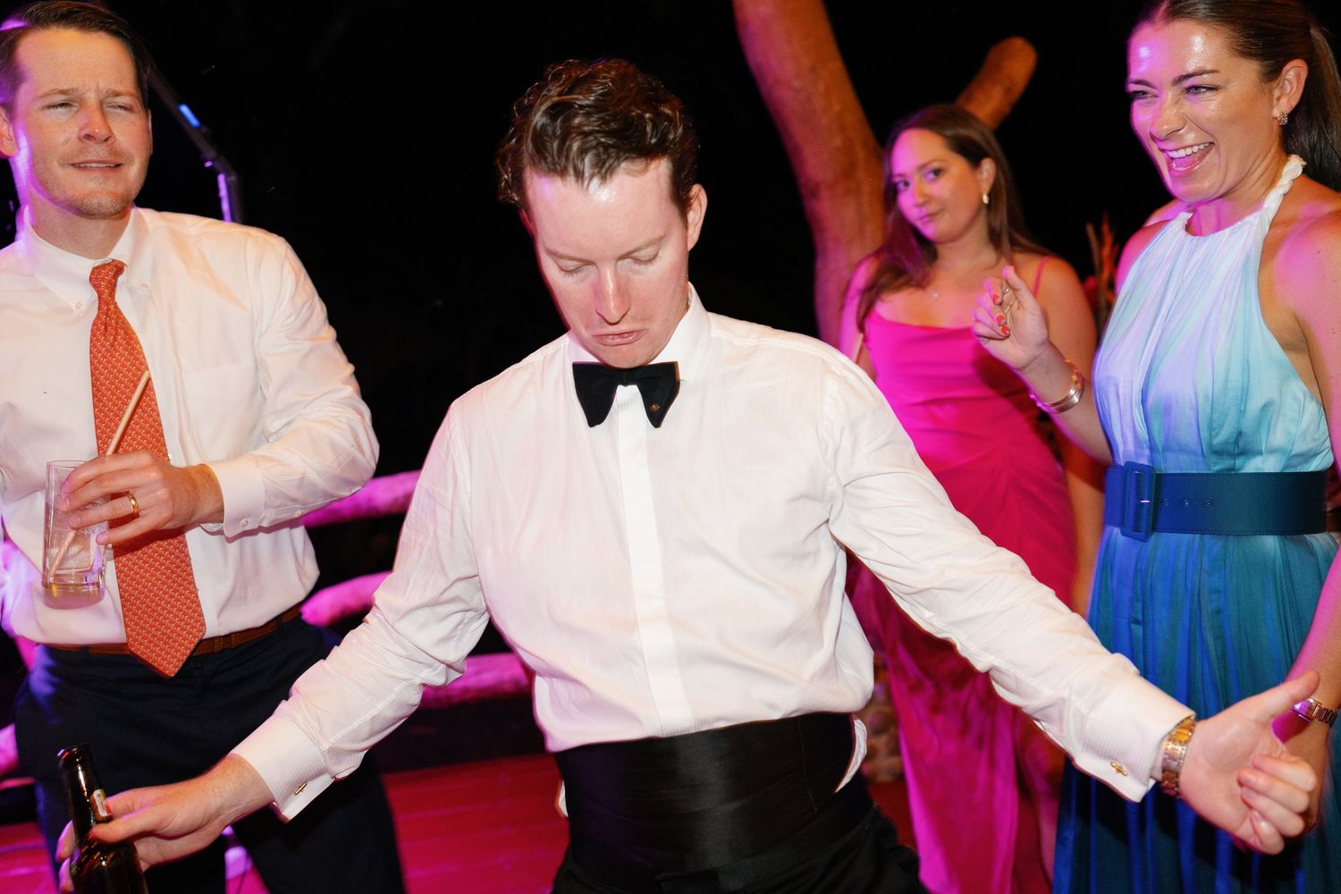 Wedding reception dance party with colorful lighting and energetic dancing.