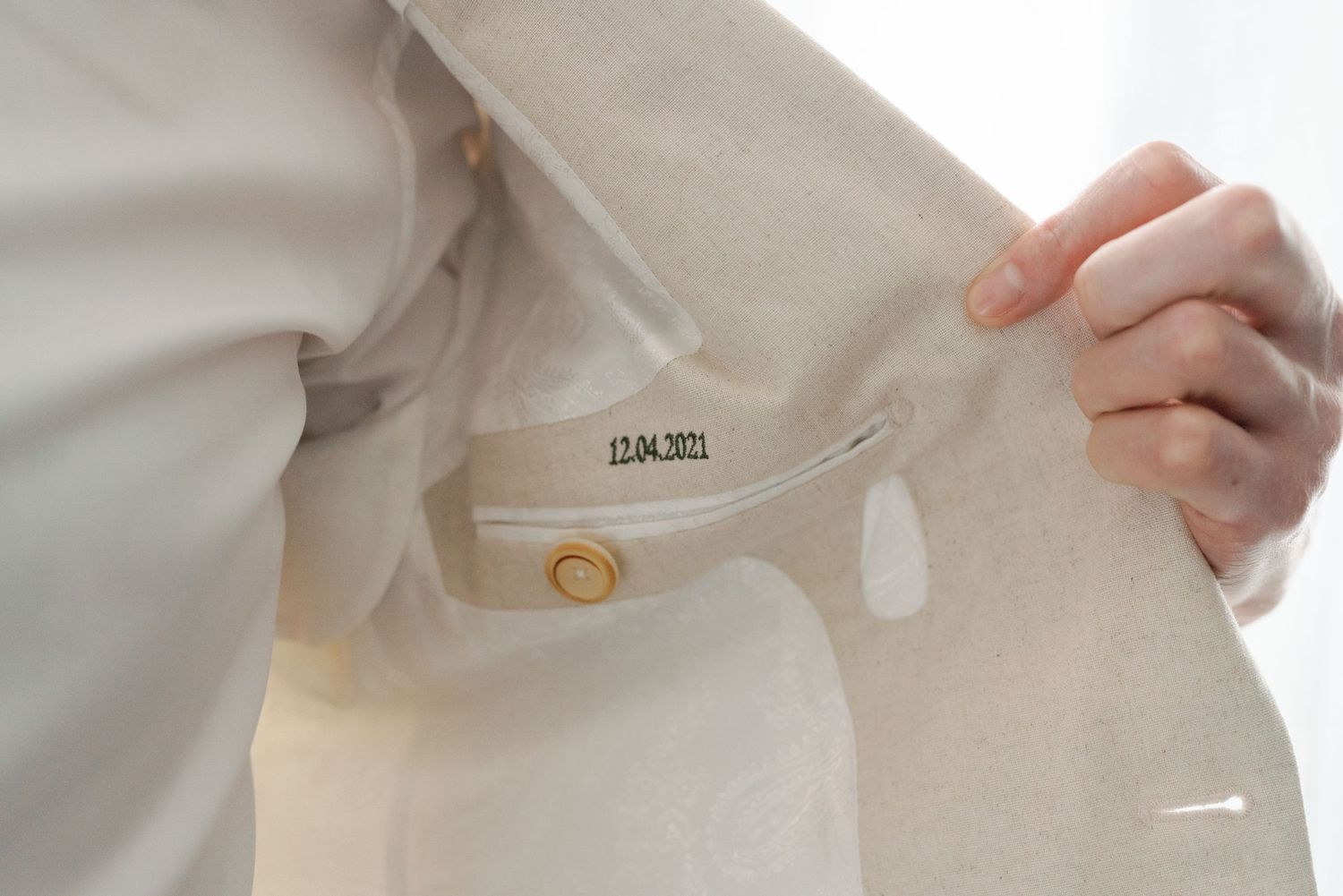 Close-up details of white wedding attire buttons and fabric.
