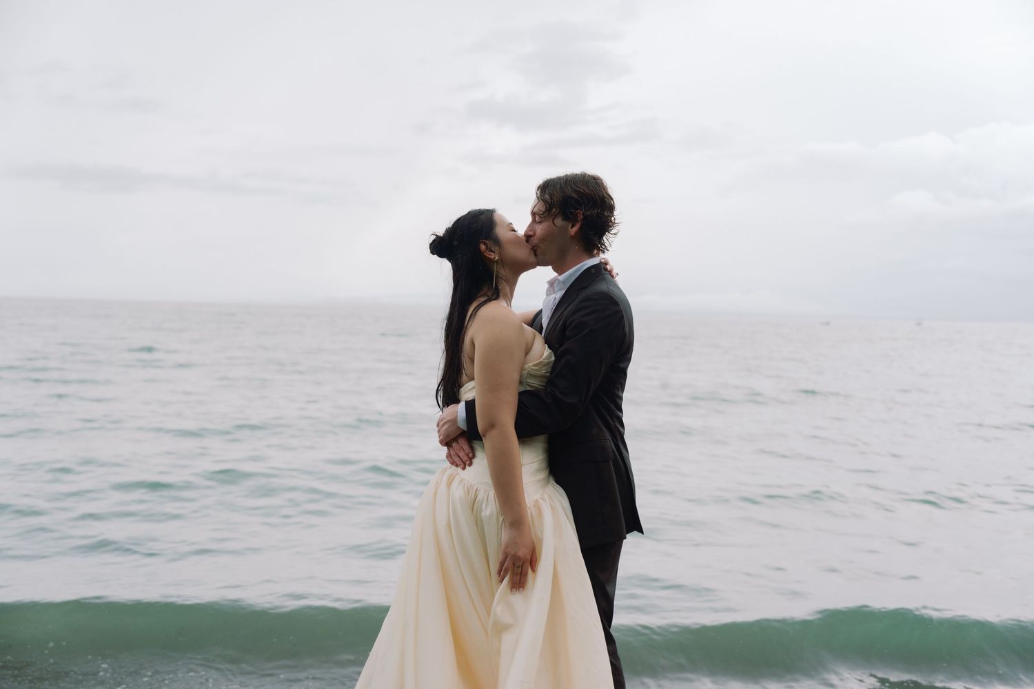 A romantic wedding moment captured against the backdrop of a misty ocean horizon.