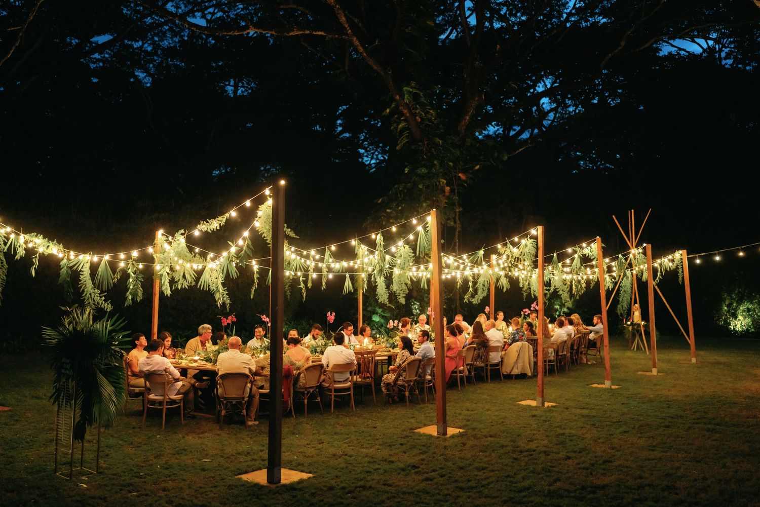 Evening outdoor wedding reception with glowing string lights creating magical ambiance.