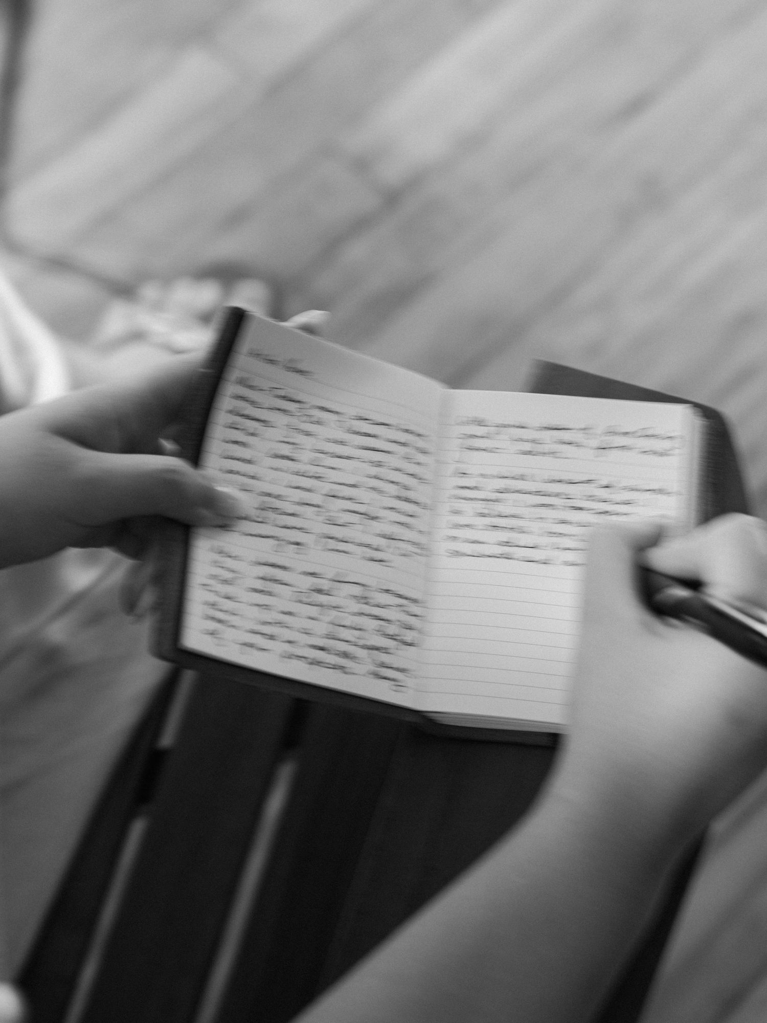 Hands holding handwritten wedding vows on white paper.