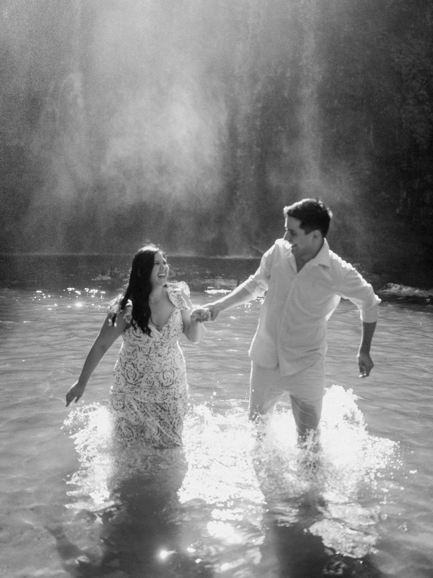 Silhouettes of a couple dancing in misty water with dramatic backlighting.