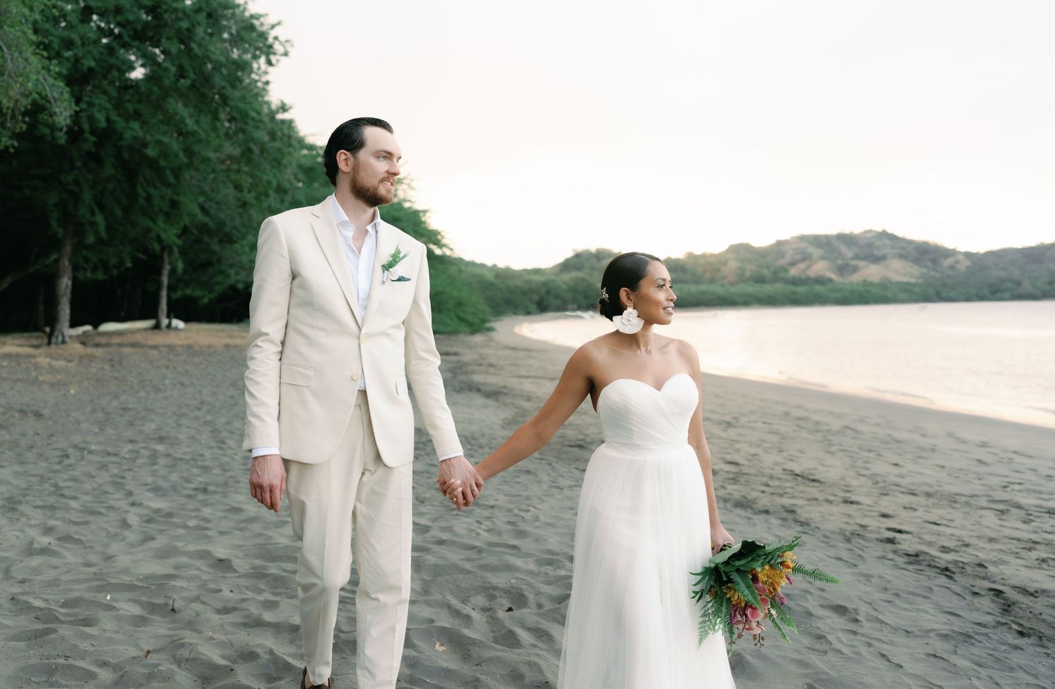 Candid beach wedding moments captured with lush greenery and ocean views.