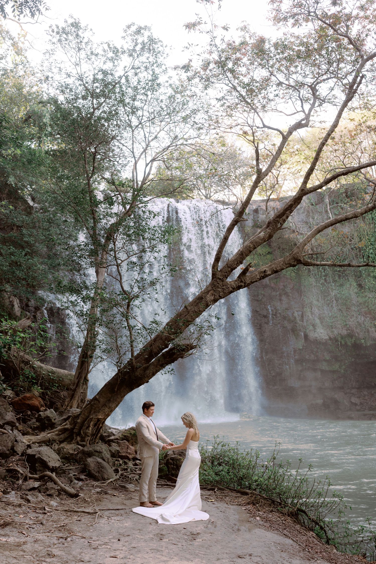 Romantic wedding photography sequence with waterfall and overhanging tree branches.