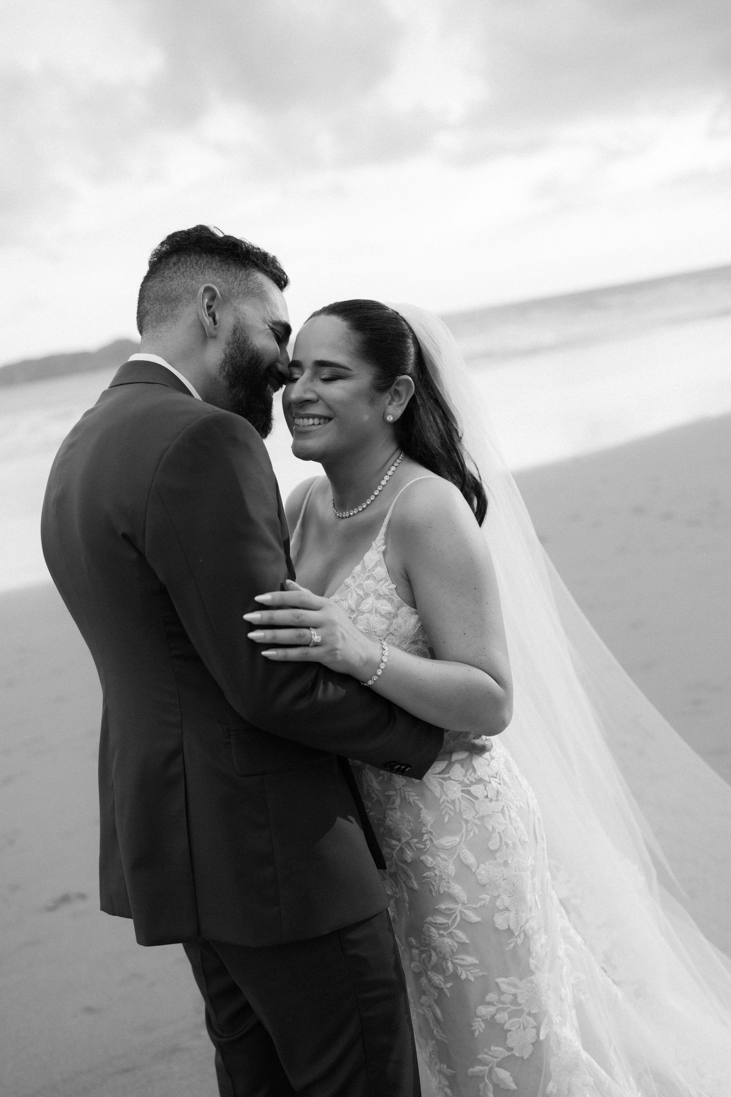 A romantic black and white wedding moment captured on a beach.