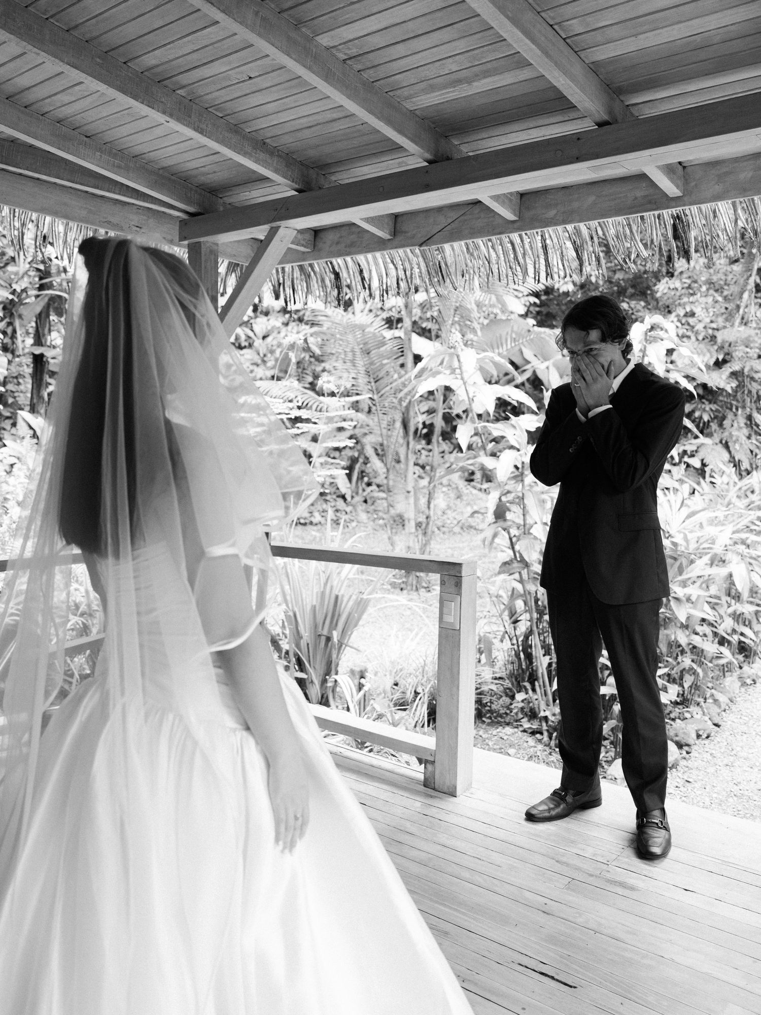 Black and white photo of first look moment between bride and groom on covered porch.