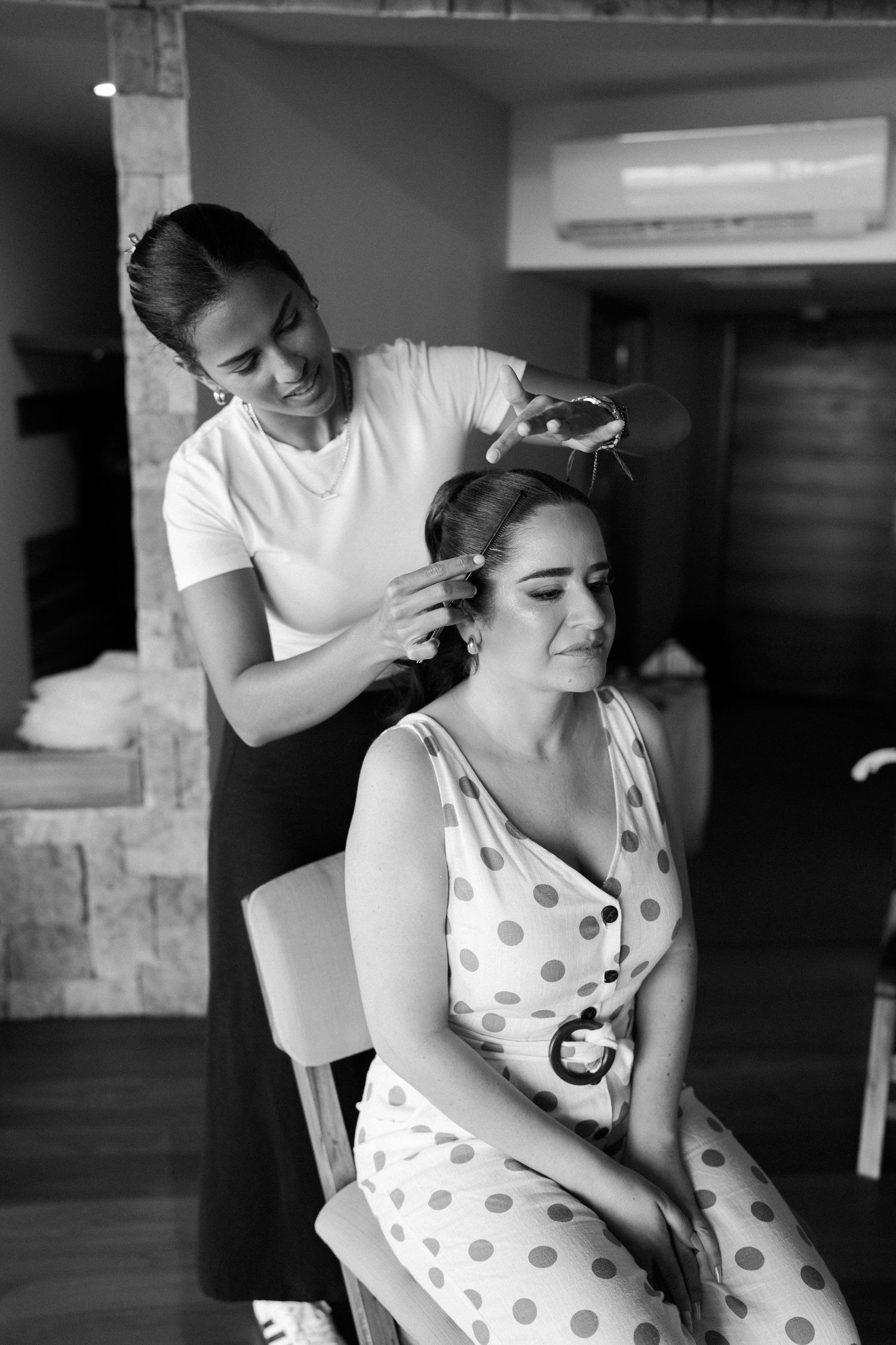 Woman in polka dot dress getting her hair and makeup styled in preparation.