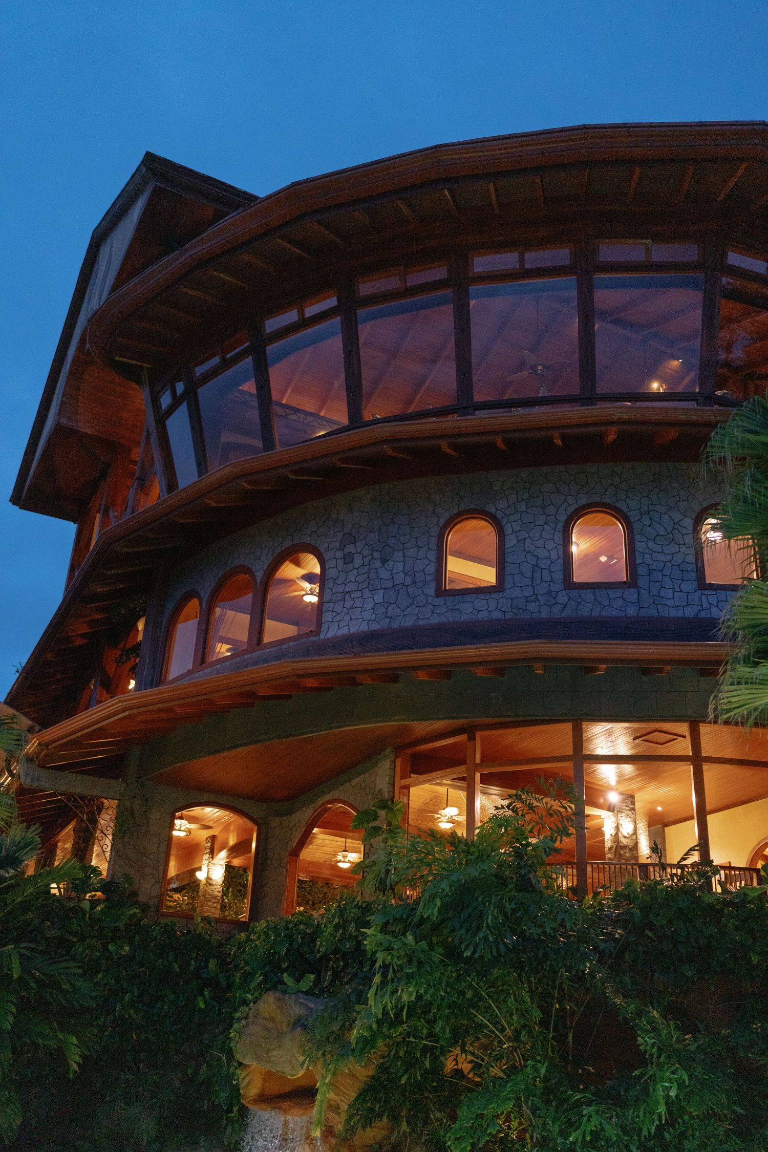 Stone and wood luxury resort building with curved architecture at sunset.