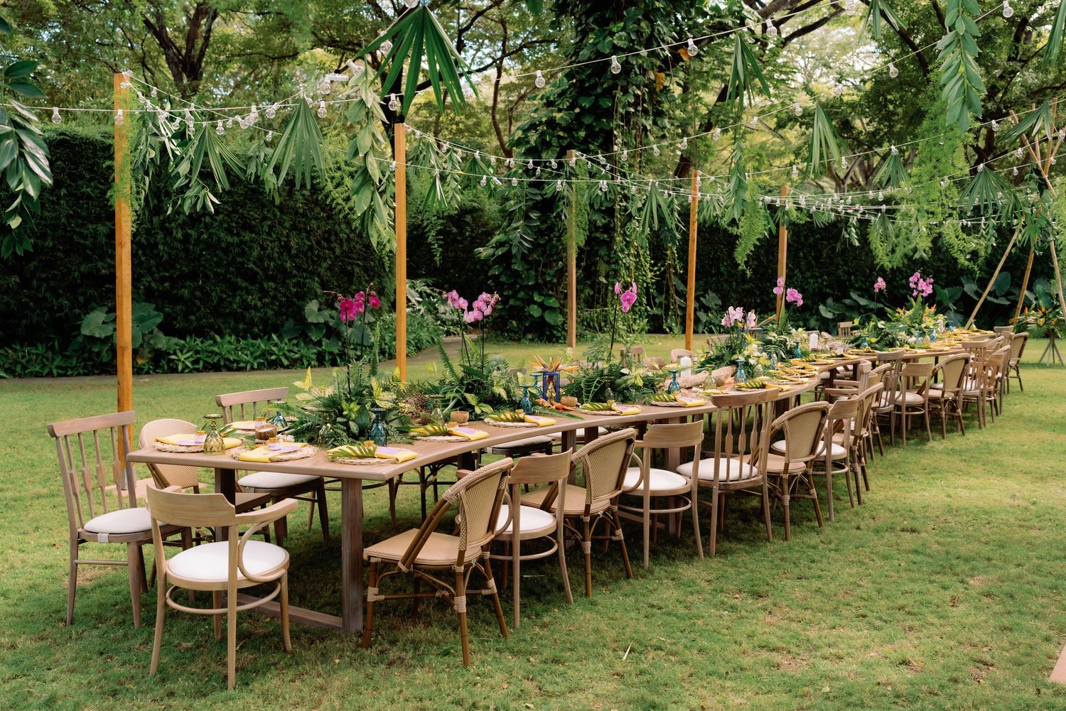 Long wooden tables and chairs set up outdoors for a garden wedding reception.